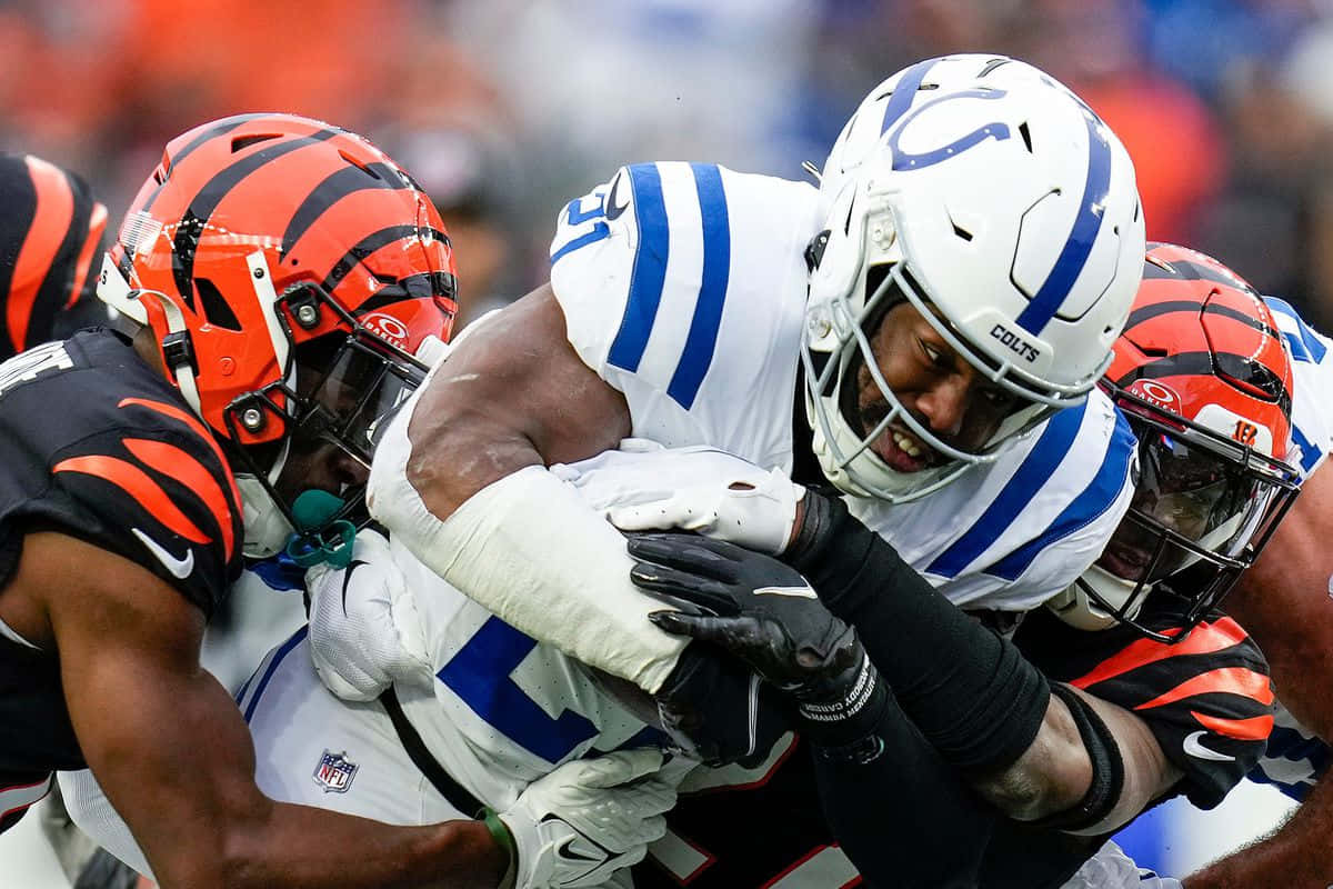  壁紙 — 印第安納波利斯小馬隊球員在激烈的NFL美式足球比賽中擒抱辛辛那提猛虎隊球員的近距離動作鏡頭。