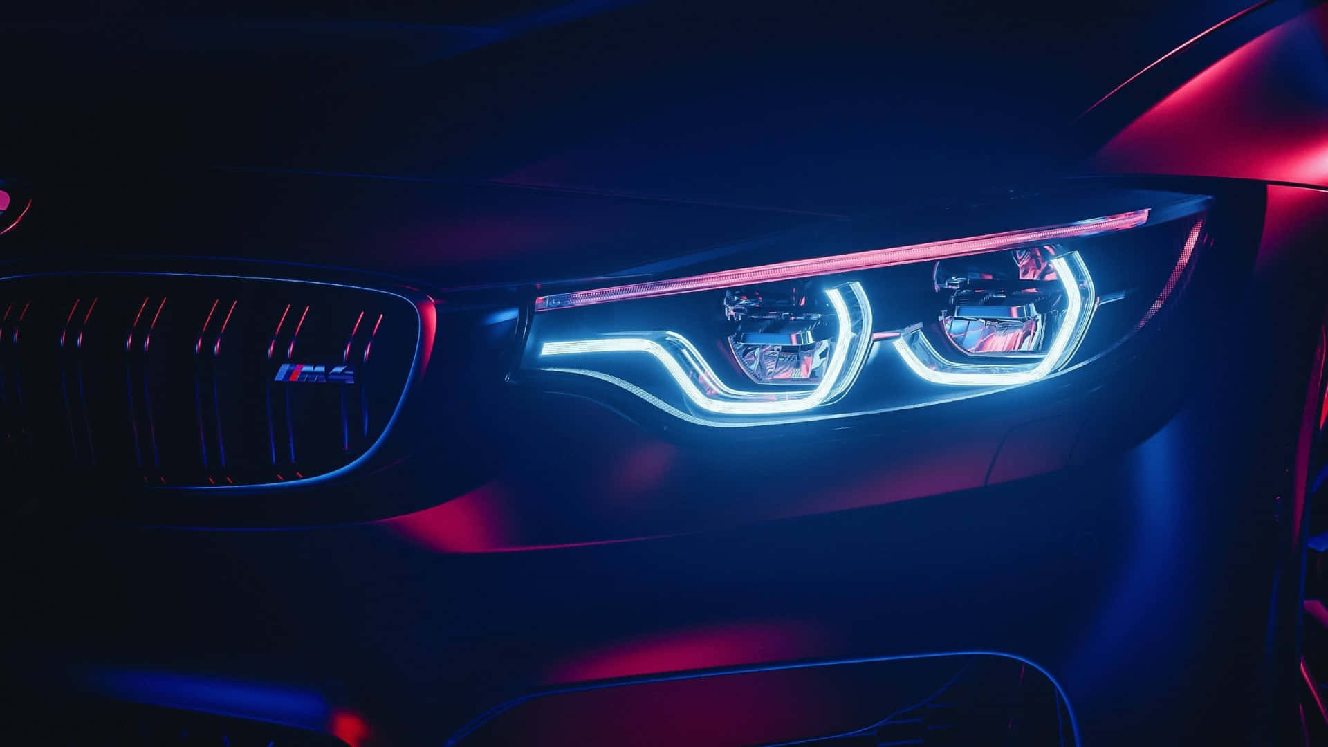  壁紙 — BMW M4 發光藍色和紅色頭燈在黑暗工作室中帶有霓虹反射的特寫。