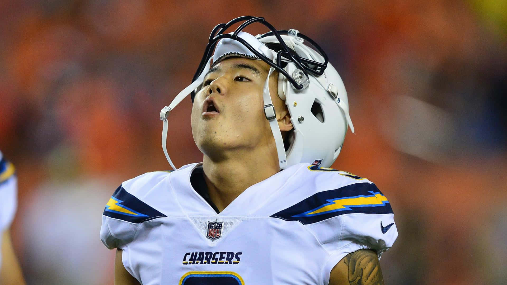  壁紙 — 一名身穿白色球衣的 Chargers 美式足球員在比賽中戴著頭盔向上看的特寫。