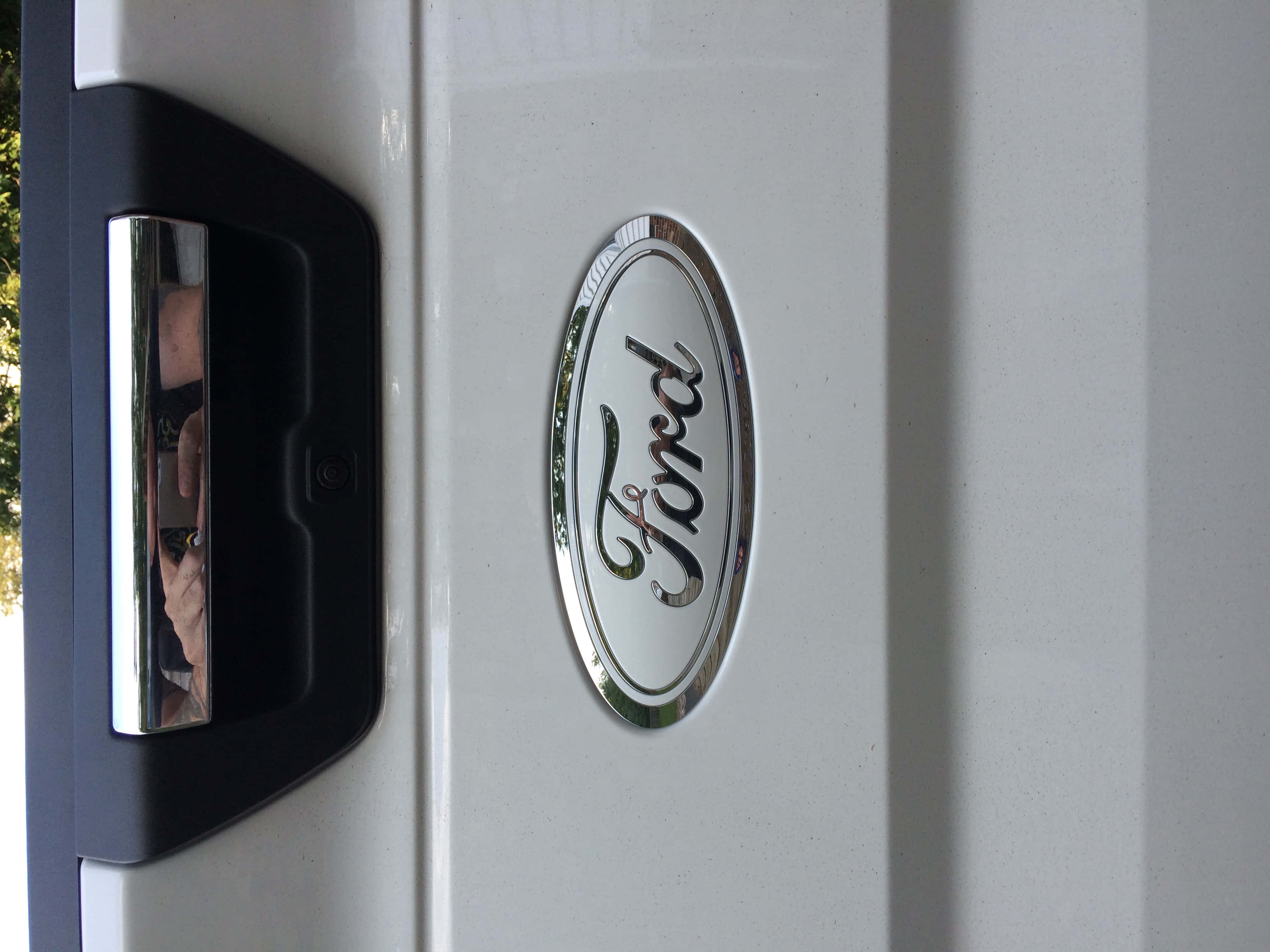 Ford Logo 桌布 壁紙 — 白色貨車門上鍍鉻福特標誌的特寫，黑色把手反射出一個人影。