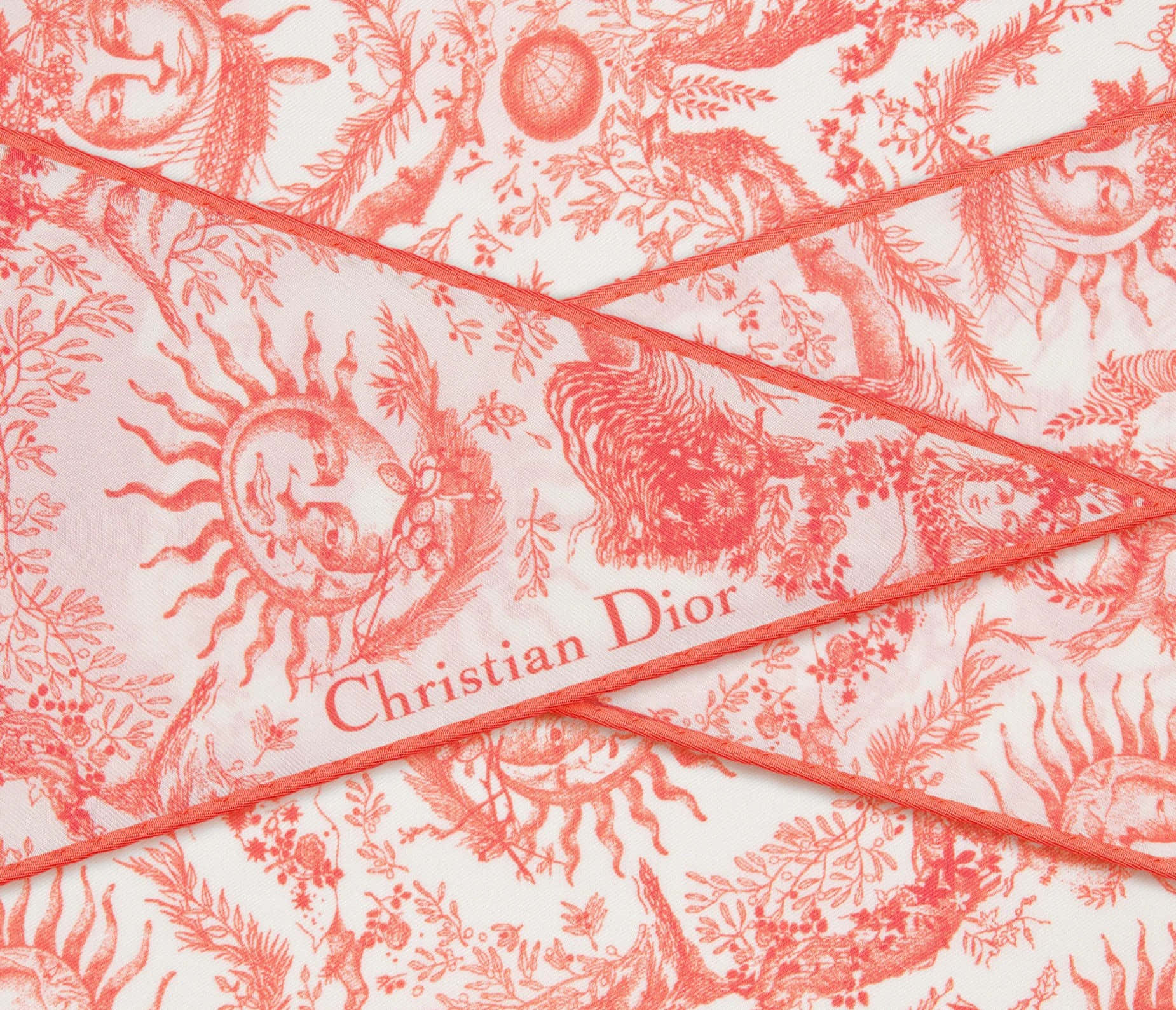 壁紙 — 白色背景上帶有太陽臉和樹葉的複雜 toiles de jouy 圖案的珊瑚色 Christian Dior 圍巾特寫。
