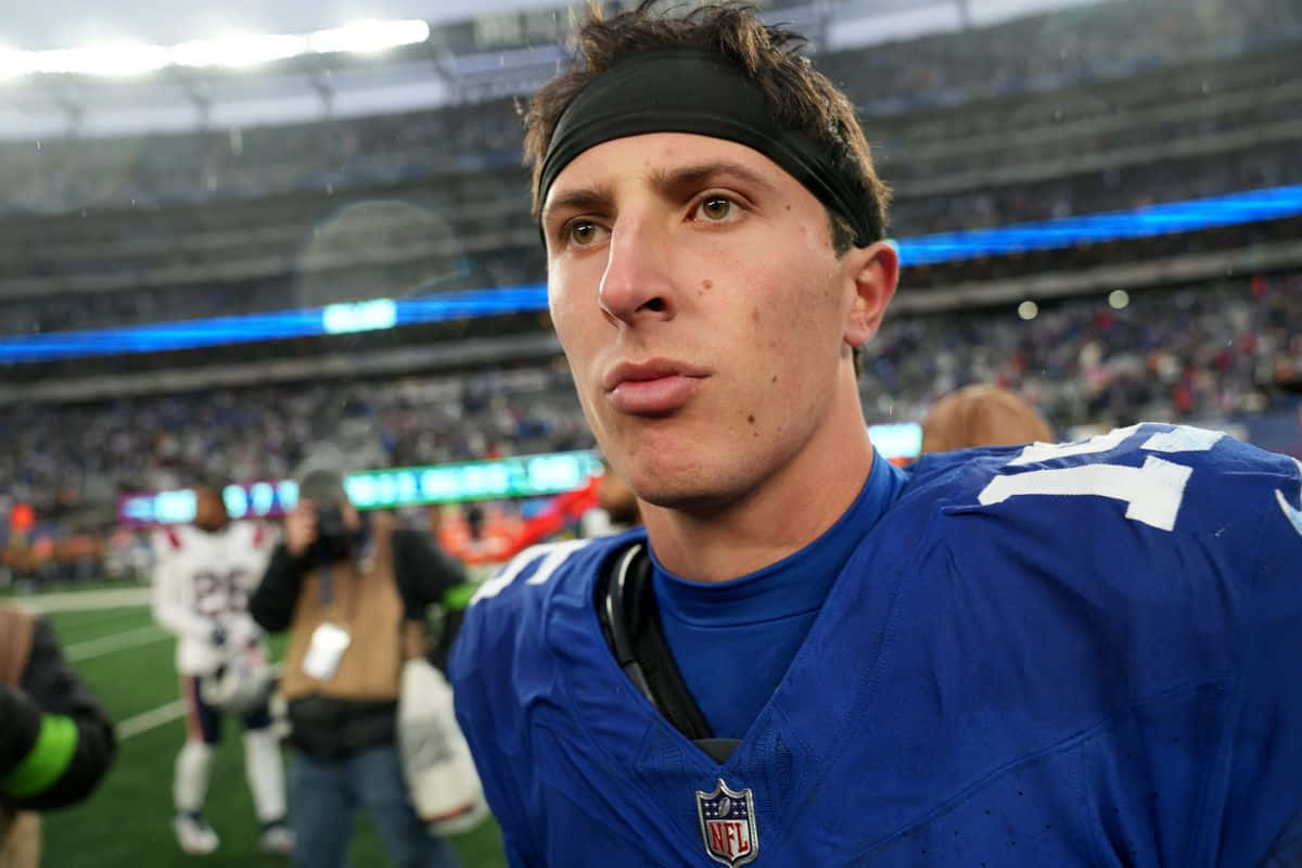  壁紙 — 近距離拍攝一位專注的NFL球員，身穿藍色17號球衣，在雨中的球場上專注地望向鏡頭外。