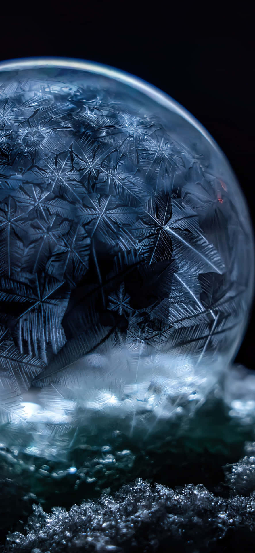  壁紙 — 一個冰凍氣泡的特寫，帶有複雜的冰晶，在黑暗背景下發光。