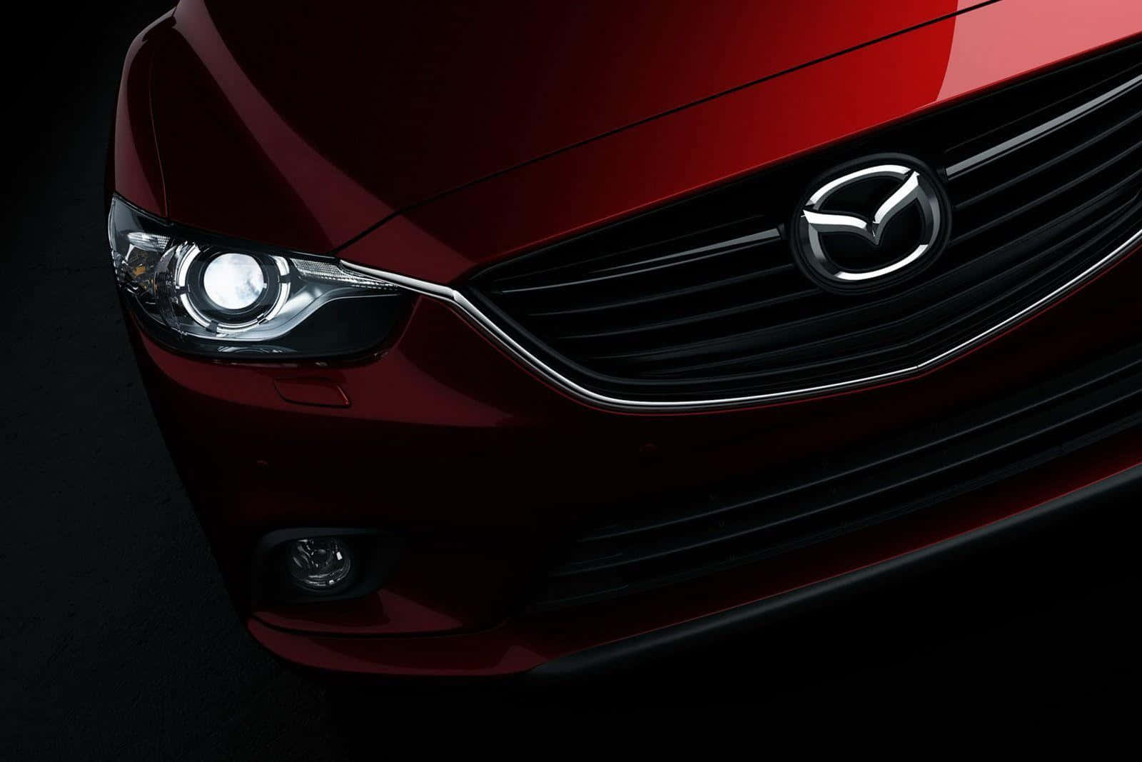 Mazda 6 桌布 壁紙 — 特寫鏡頭：一輛亮紅色馬自達汽車的前格柵和頭燈，背景為深色。