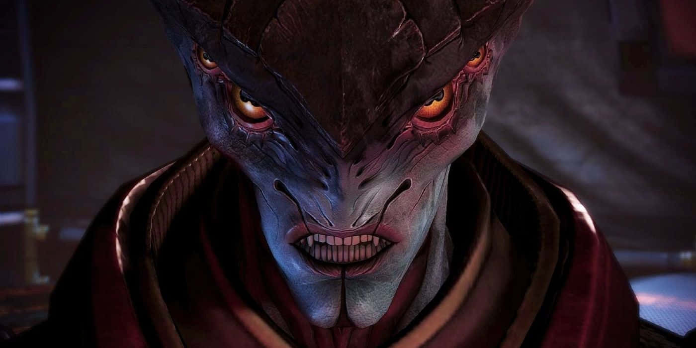 Mass Effect Javik 桌布 壁紙 — 近距離拍攝一個帶有發光橙色眼睛和尖銳牙齒、身穿紅色斗篷的威脅性外星人，處於昏暗光線中。