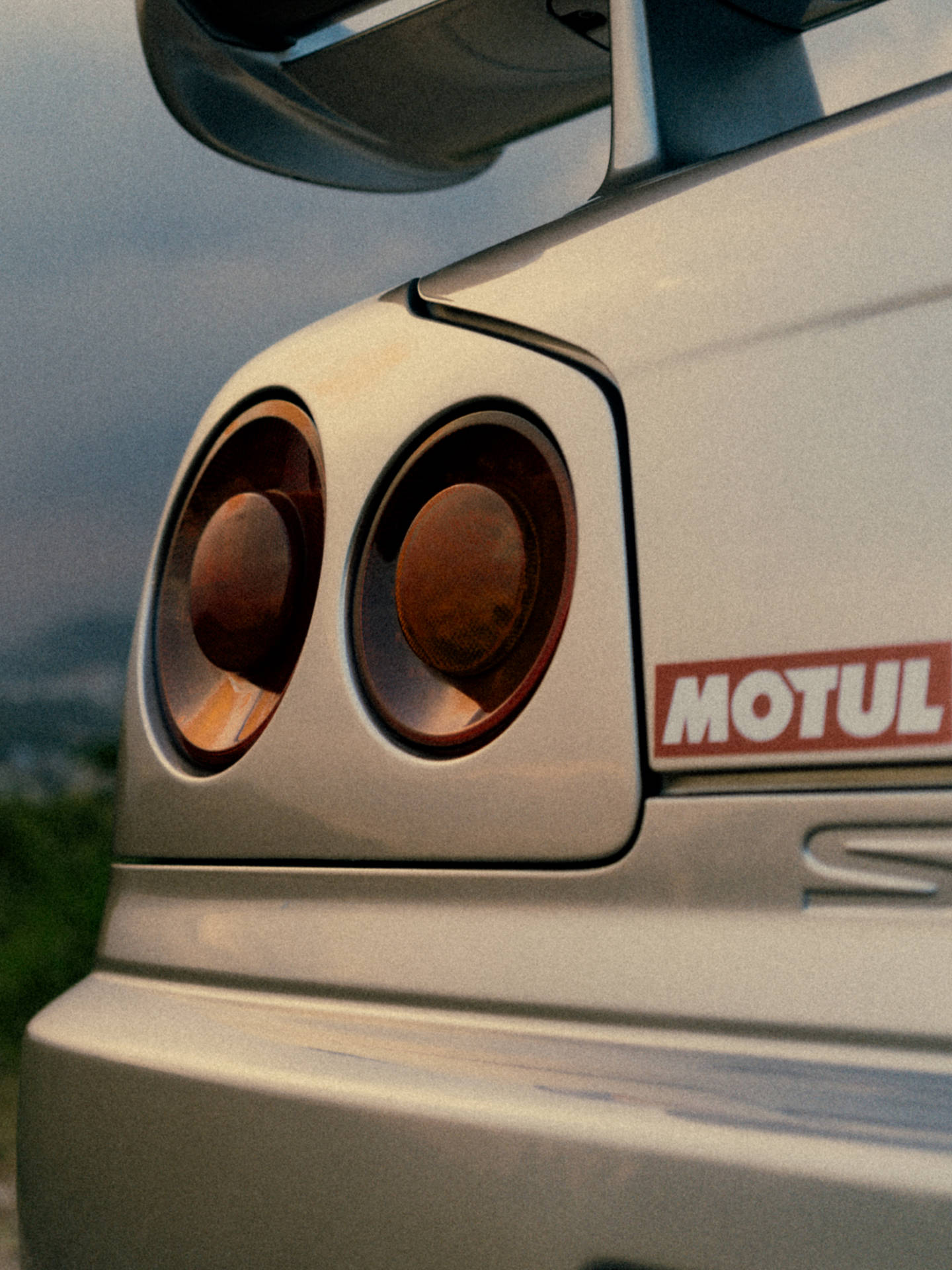 銀色跑車尾部，帶有圓形尾燈和 Motul 貼紙。 — 日產 Skyline GTR R34 壁紙