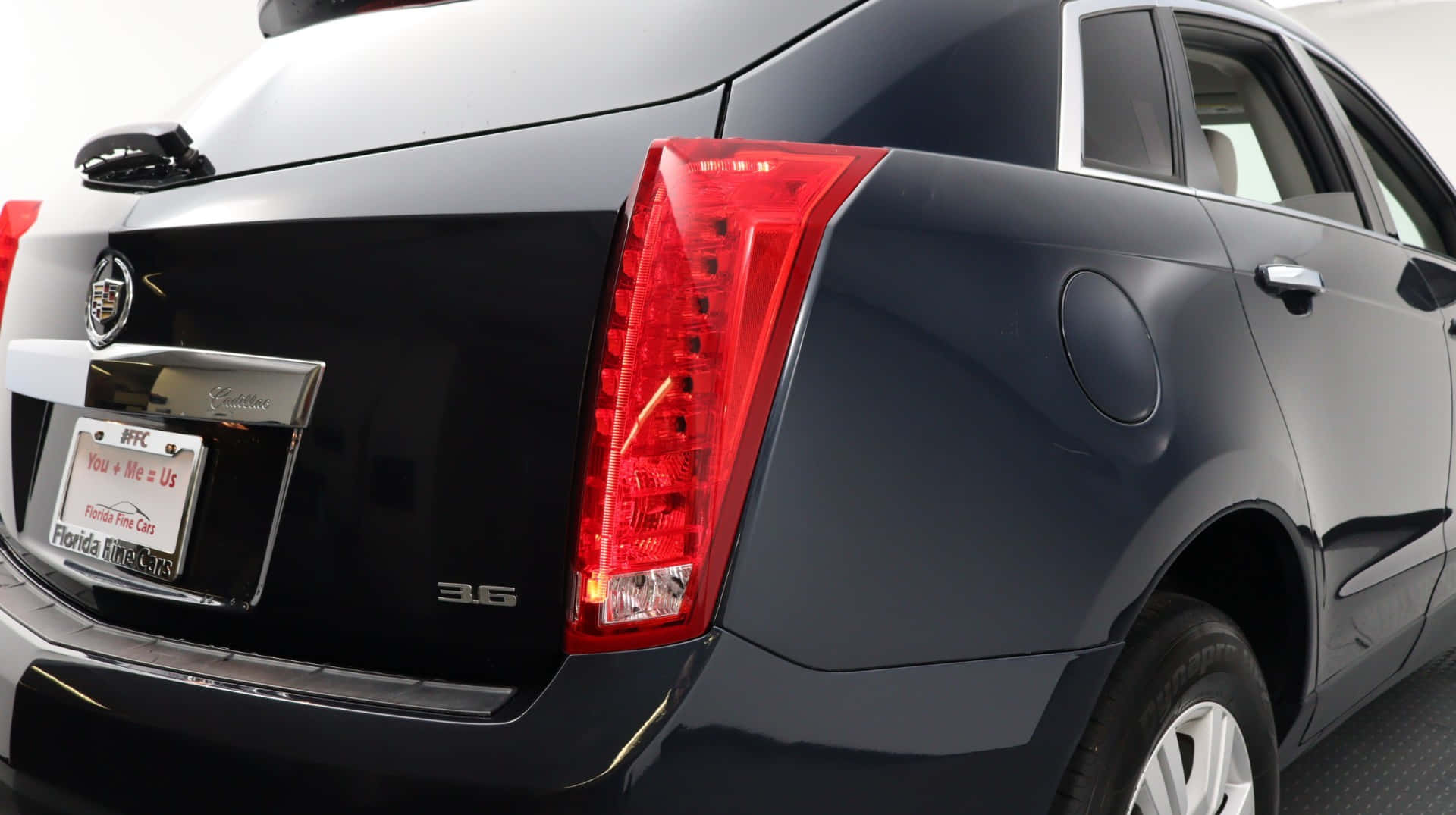 Cadillac Srx 桌布 壁紙 — 近距離拍攝時尚黑色 Cadillac 轎車的尾部，在明亮的攝影棚燈光下展示其大膽的紅色尾燈和鍍鉻裝飾。