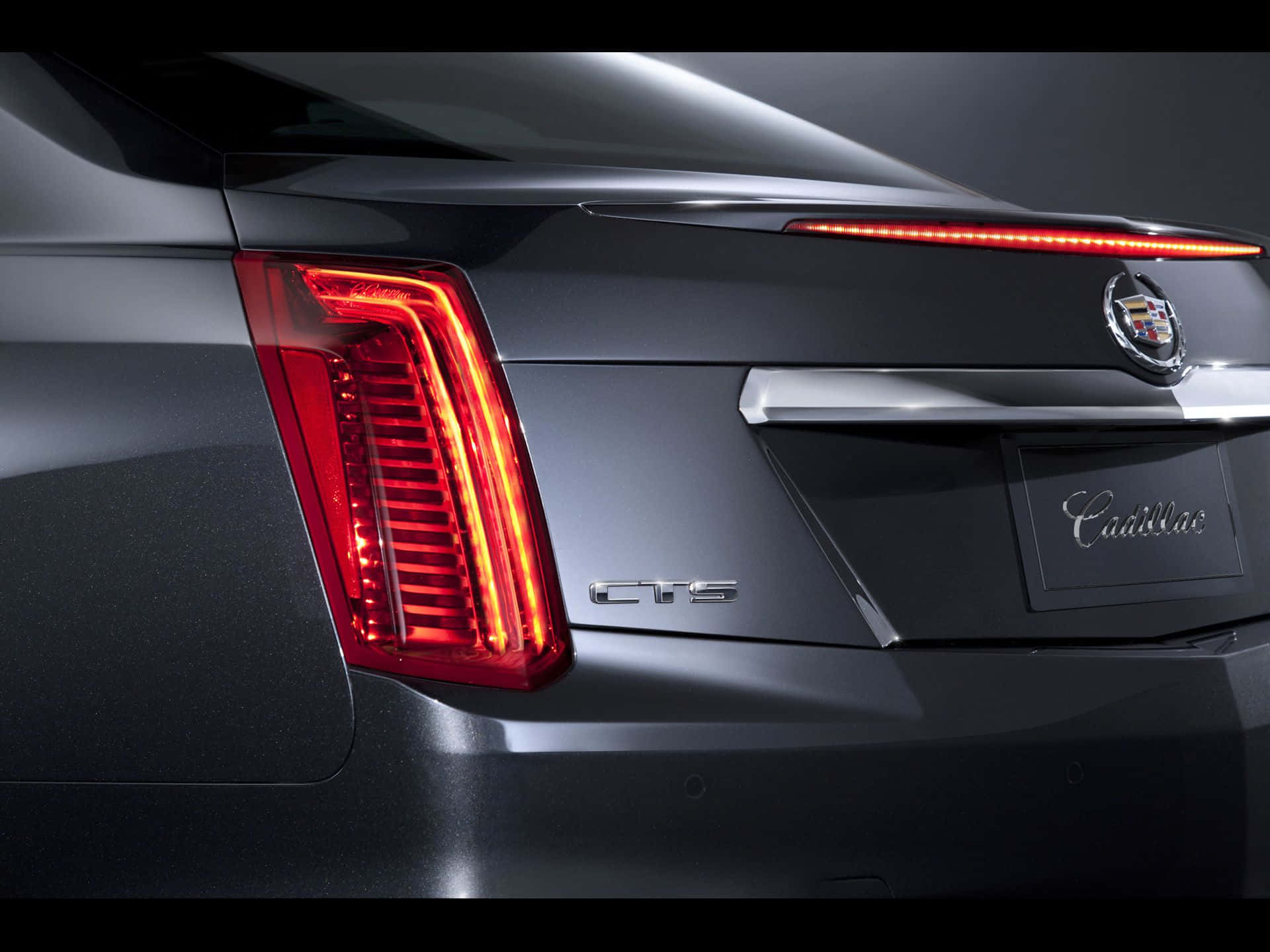 Cadillac Cts 桌布 壁紙 — 近距離拍攝時尚深灰色Cadillac CTS車尾，展示在工作室燈光下發光的紅色LED尾燈和鍍鉻裝飾。