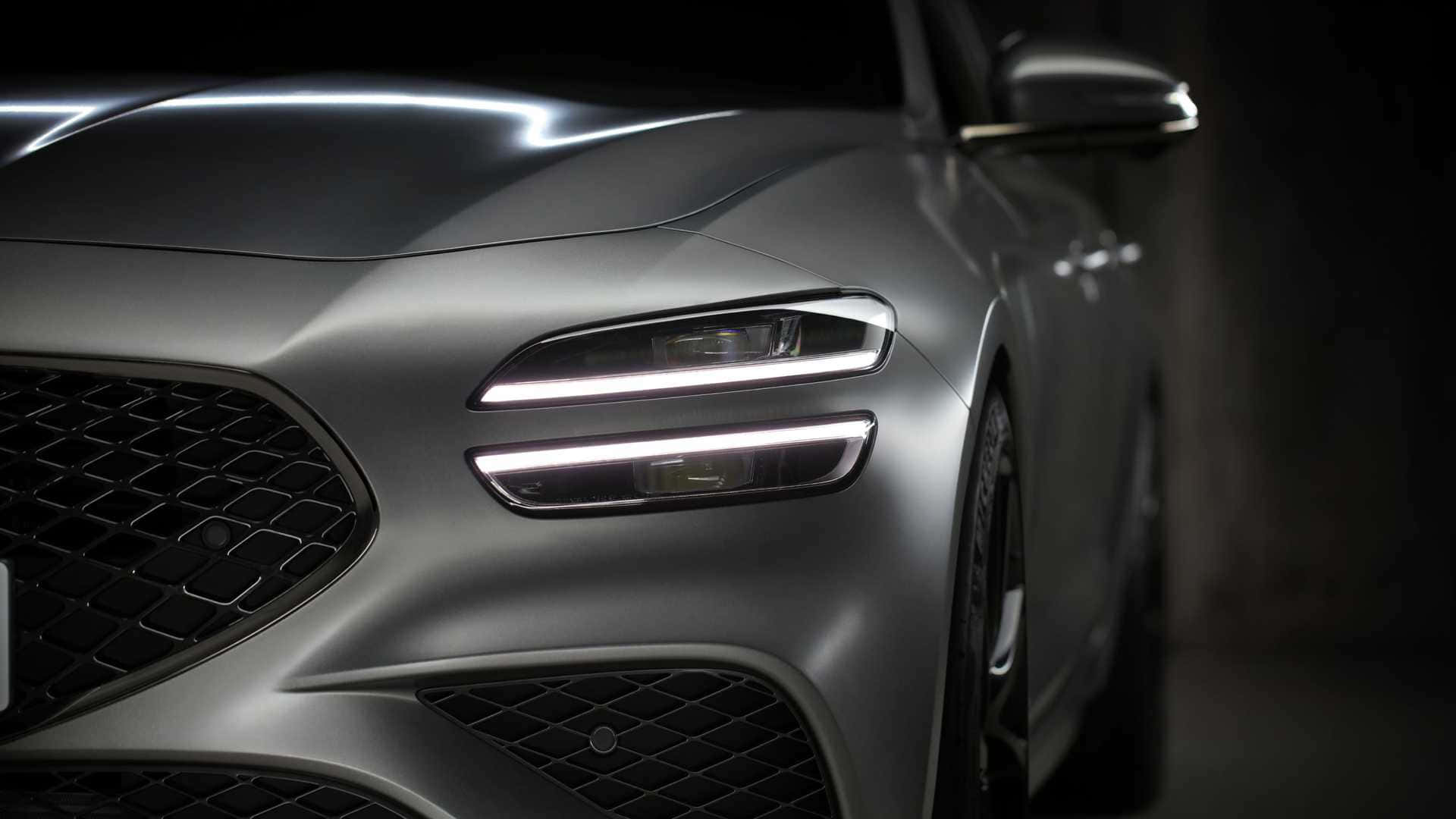 Genesis G70 桌布 壁紙 — 特寫：一輛時尚的啞光銀色跑車在黑暗背景下發光的車頭燈。
