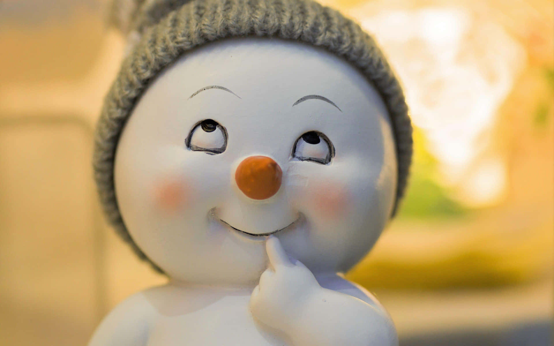 壁紙 — 一個微笑雪人公仔的近距離特寫，戴著針織帽，手指若有所思地放在下巴上。