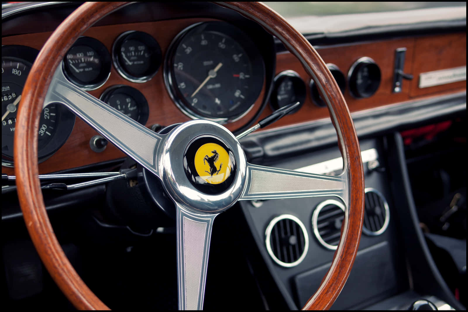 Steering Wheel 桌布 壁紙 — 經典法拉利方向盤特寫，採用木質飾邊、鍍鉻輻條和標誌性的躍馬標誌。