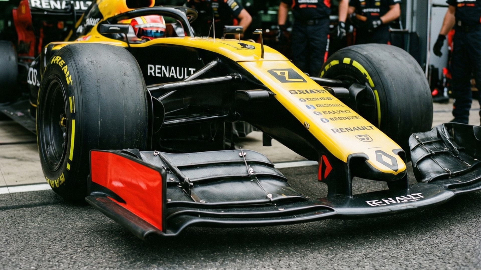 F1 Pit Detail 壁紙 — 一輛黃黑相間的雷諾F1賽車帶有紅色點綴，停在瀝青路面上，附近有車隊成員的近距離特寫。