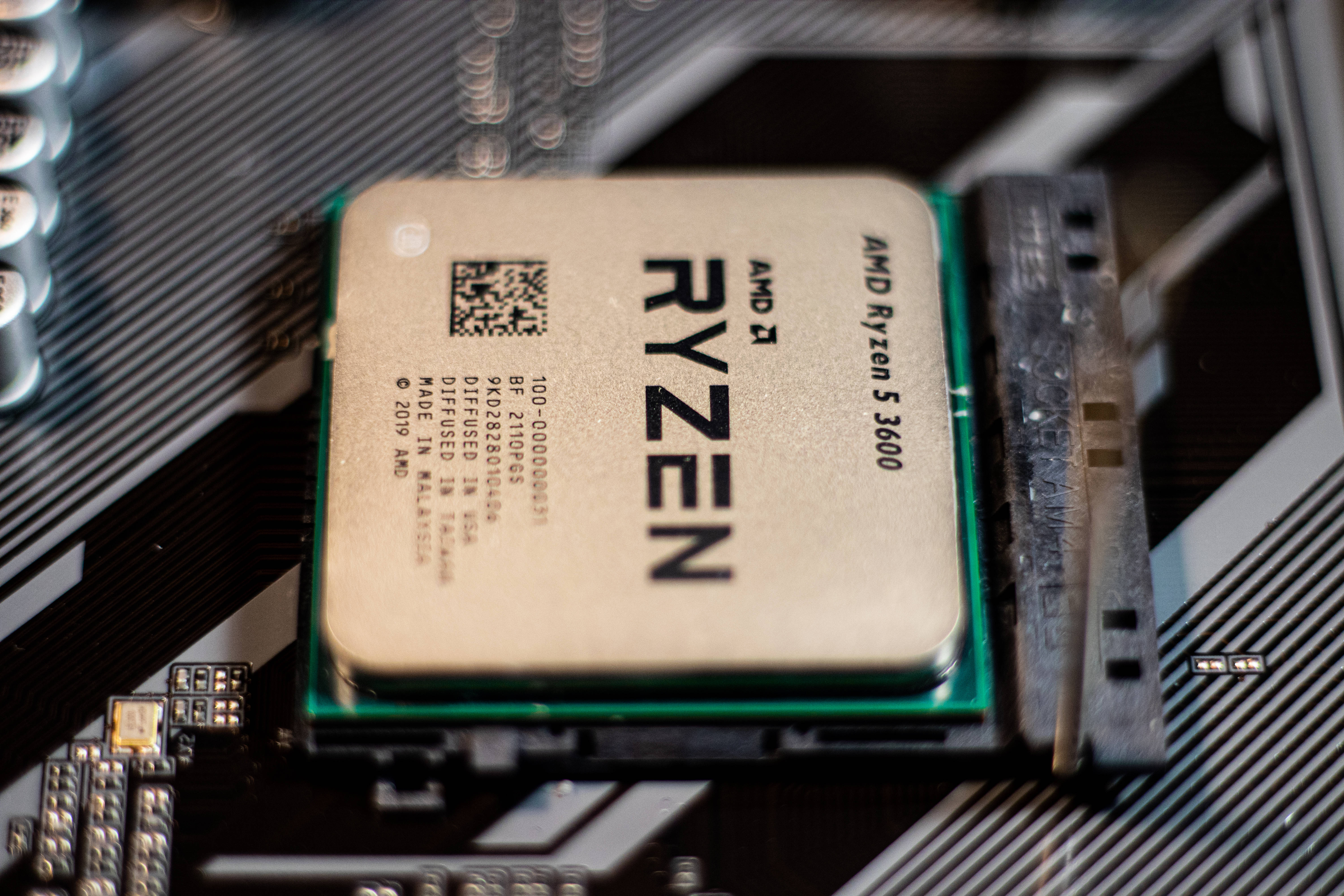 Motherboard 桌布 壁紙 — AMD Ryzen 5 3600 CPU 安裝在主機板上的特寫，可見電路和金屬光澤。