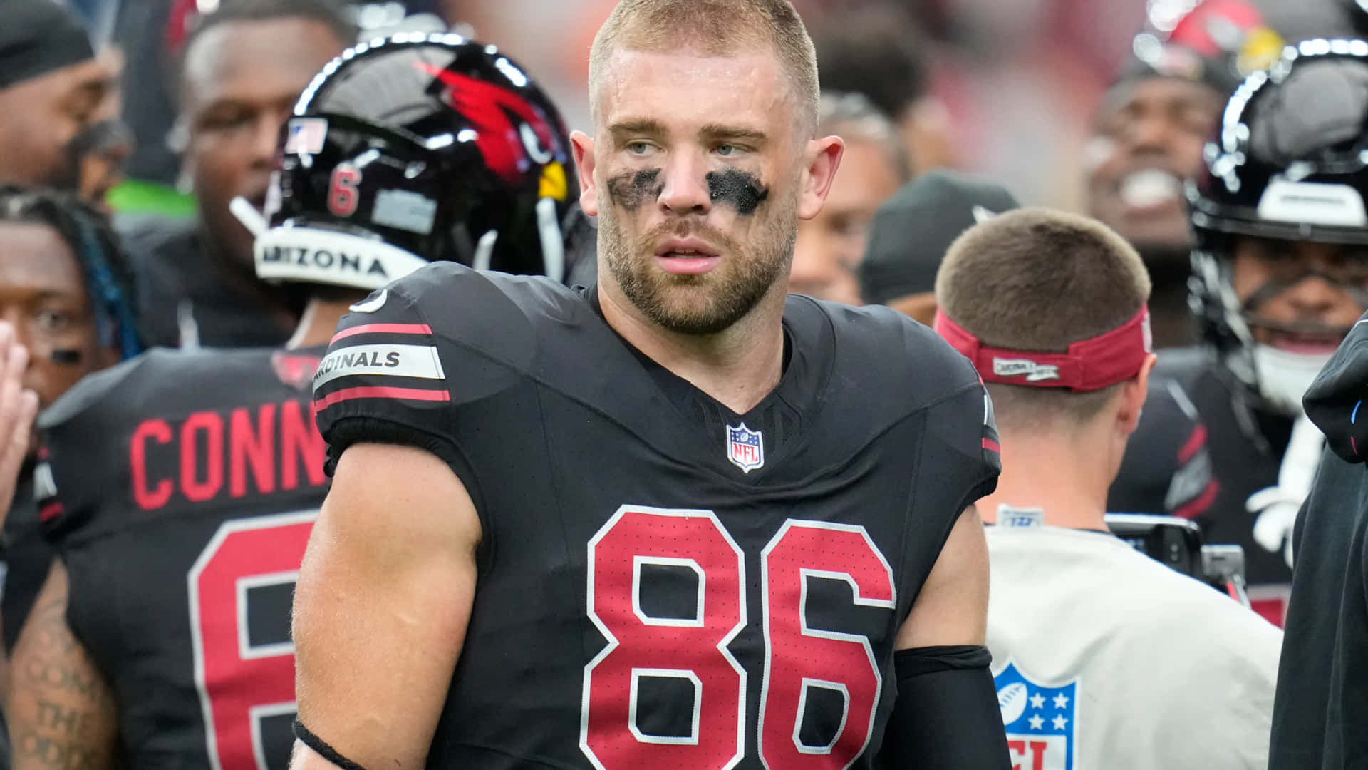  壁紙 — NFL 美式足球員身穿黑色球衣，紅色86號碼，黑色眼影，站在球場上的特寫。