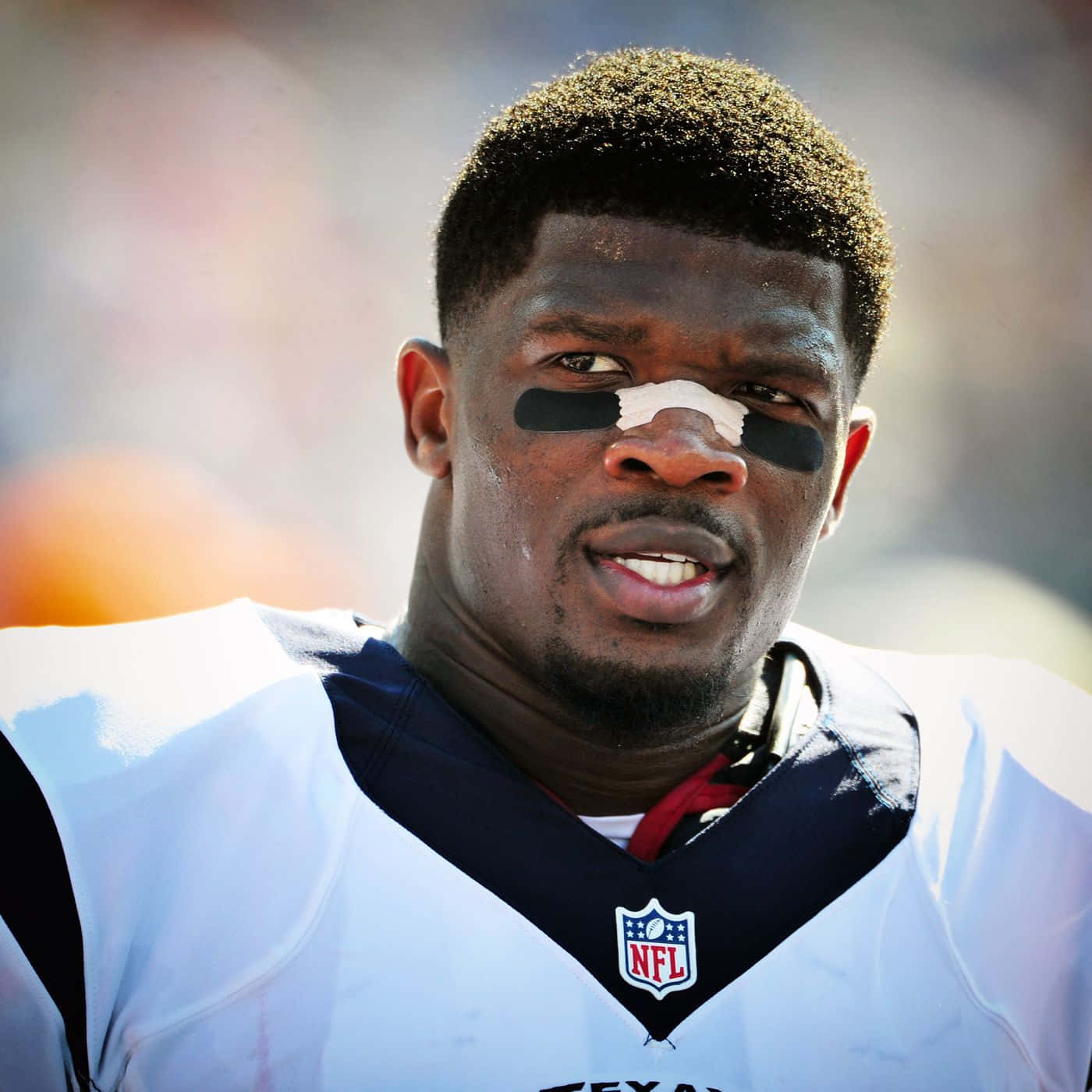  壁紙 — NFL 美式足球員近照，臉上塗有黑白顏料，身穿白色球衣，在明亮日光下。