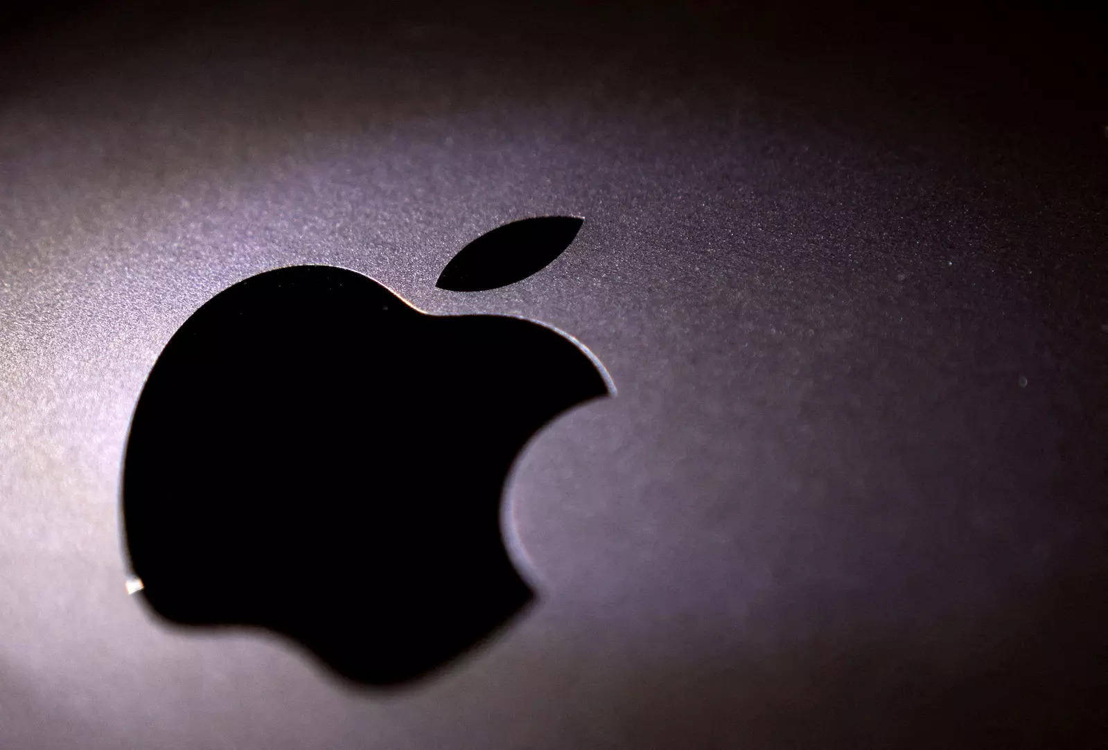 Apple 標誌鏤空在深灰色表面上，柔和光線 — 3D 壁紙