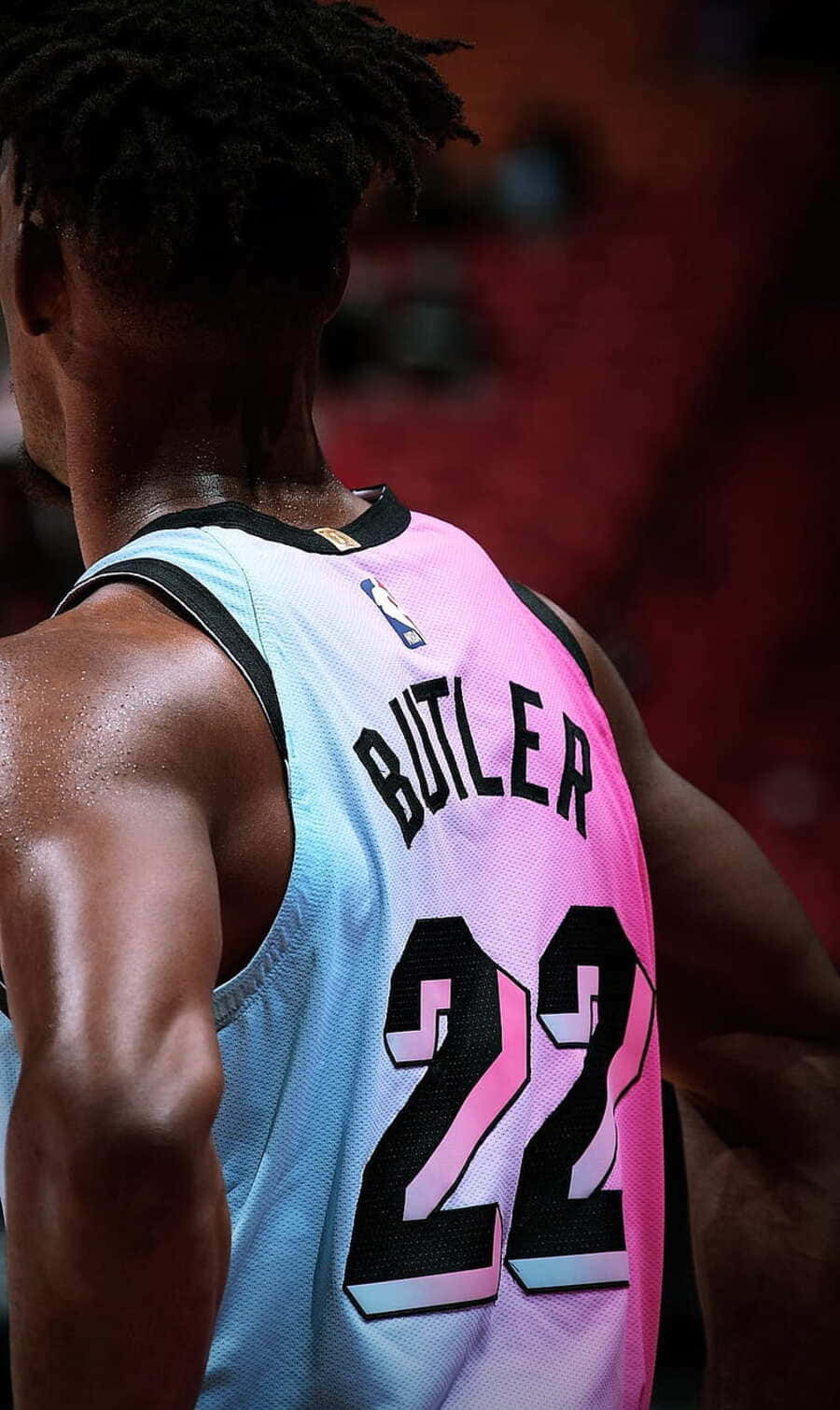  壁紙 — 籃球運動員吉米·巴特勒的特寫，身穿漸層粉紅和藍色球衣，號碼22，從後方在球場上觀看。