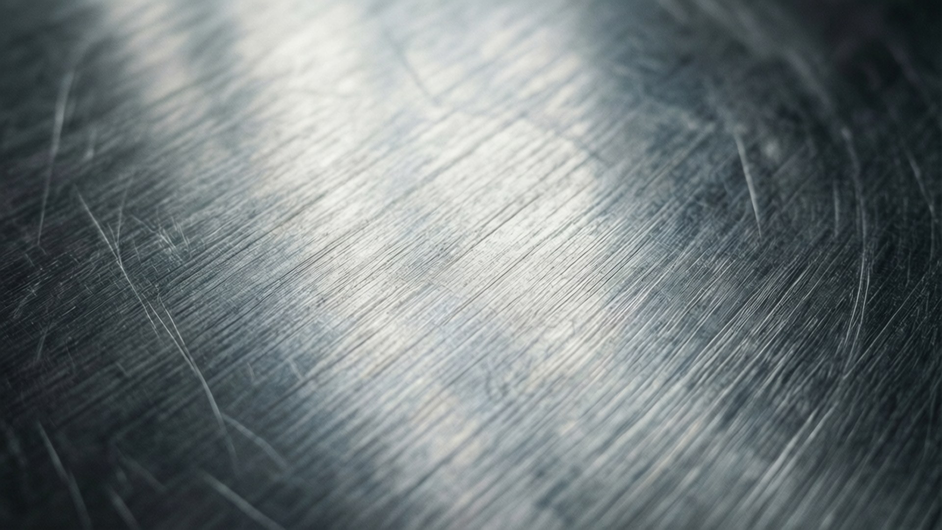 Brushed Aluminum Texture 壁紙 — 拉絲金屬表面的特寫，帶有對角線刮痕和柔和漸變照明。