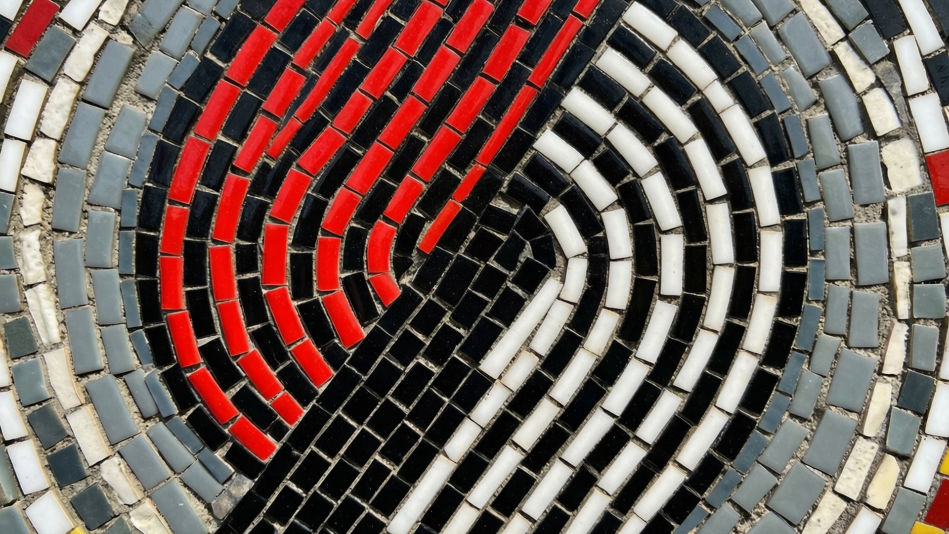 Mosaic Tile Pinwheel Art 壁紙 — 由紅色、黑色、白色和灰色瓷磚組成的圓形馬賽克藝術品特寫，形成同心彎曲圖案。