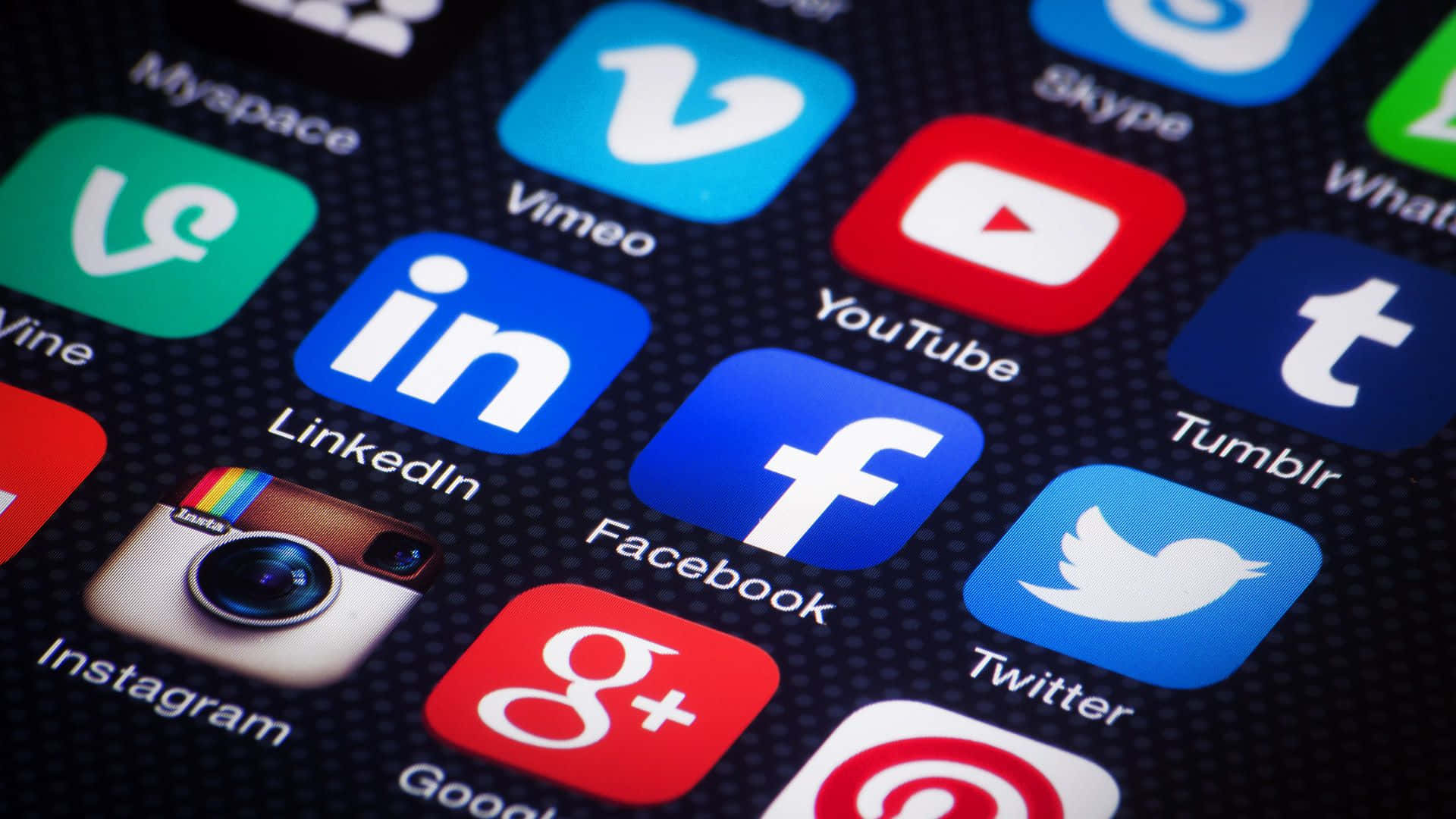 4K Social Media 桌布 壁紙 — 智慧型手機螢幕上色彩繽紛的社交媒體應用程式圖示在深色紋理背景上發光的特寫。