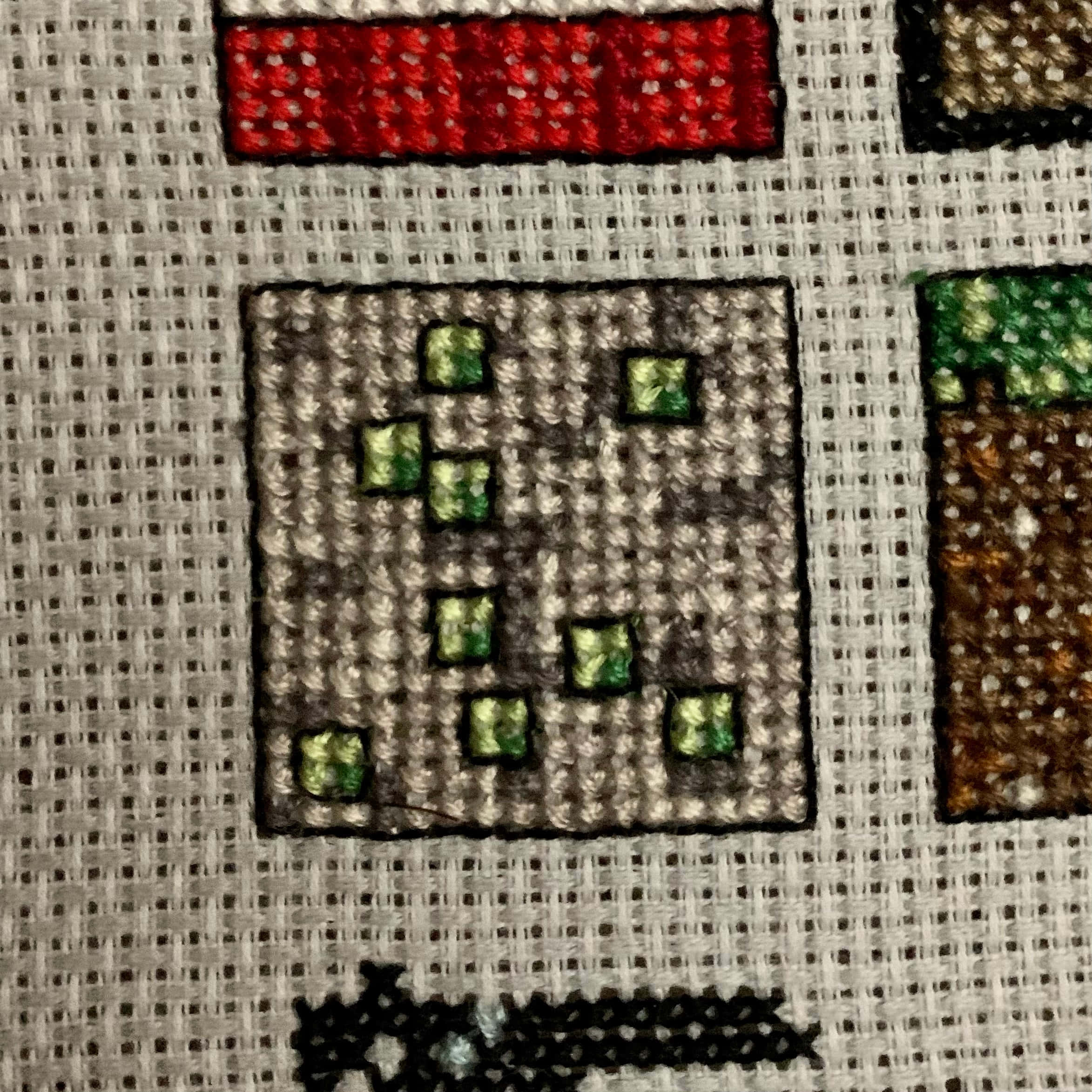 Minecraft Emeralds 桌布 壁紙 — 刺繡十字繡的特寫，在帶有紋理的布料上用鮮豔的線色描繪Minecraft方塊。