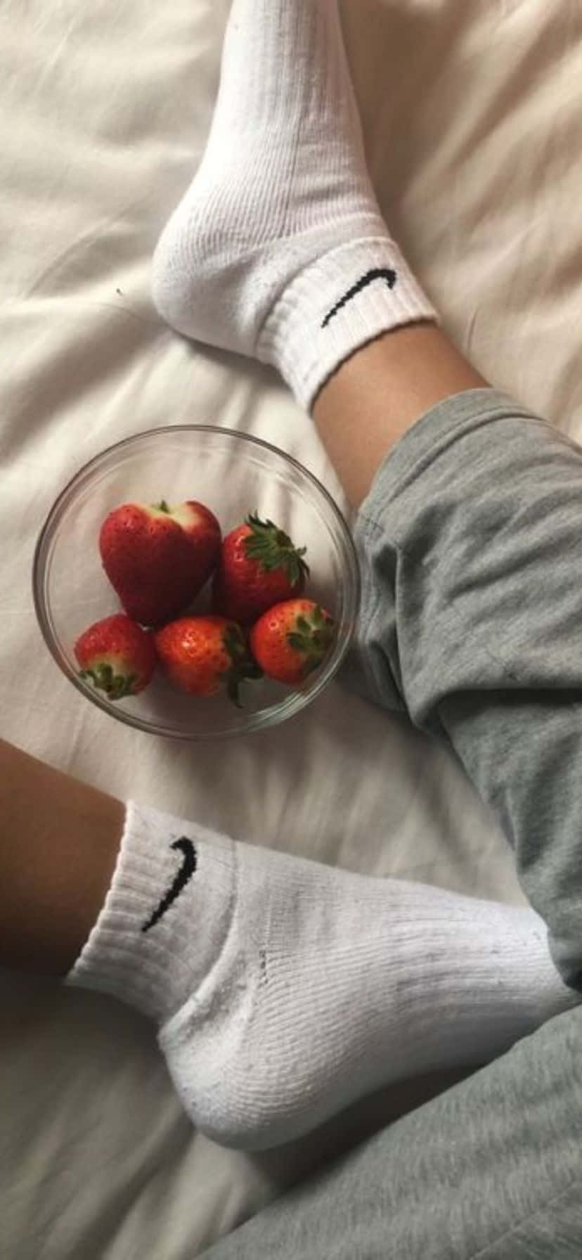  壁紙 — 雙腳穿著白色Nike襪子，在床上的新鮮草莓玻璃碗旁邊休息的特寫。