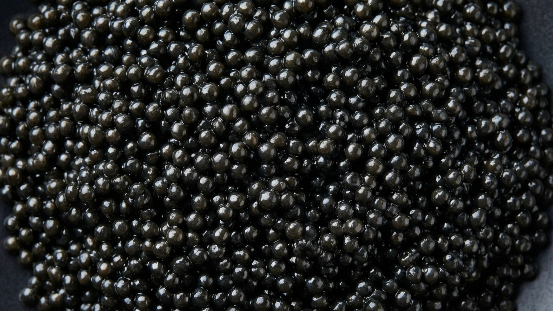 Caviar 桌布 壁紙 — 黑色碗中密集堆疊的閃亮黑魚子醬珍珠特寫。