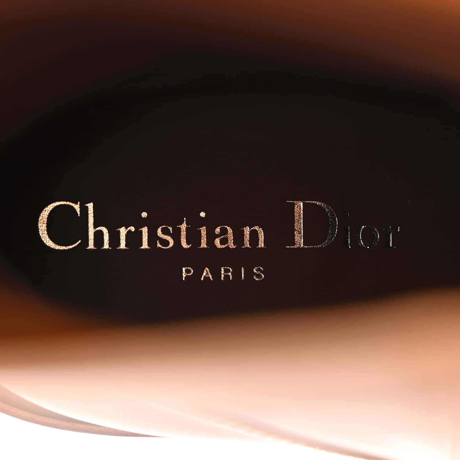  壁紙 — 金色Christian Dior Paris標誌壓印在深色皮革上的特寫，帶柔和溫暖燈光。