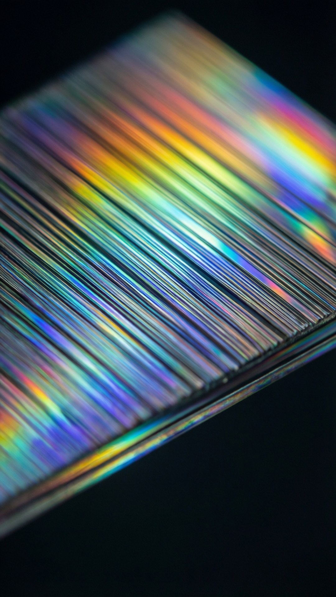 Spectroscopy 桌布 壁紙 — 黑色背景上顯示鮮豔彩虹色斜條紋的全息表面特寫。