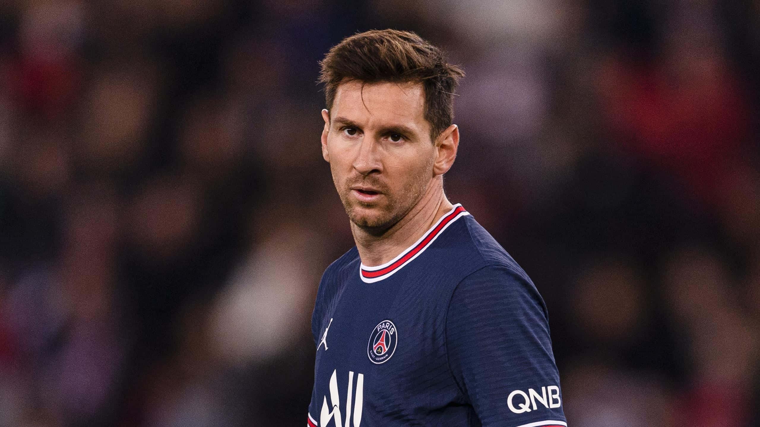 Messi 2022 桌布 壁紙 — 里奧內爾·梅西身穿巴黎聖日耳曼球衣的近距離特寫，在夜間比賽中專注地凝視。