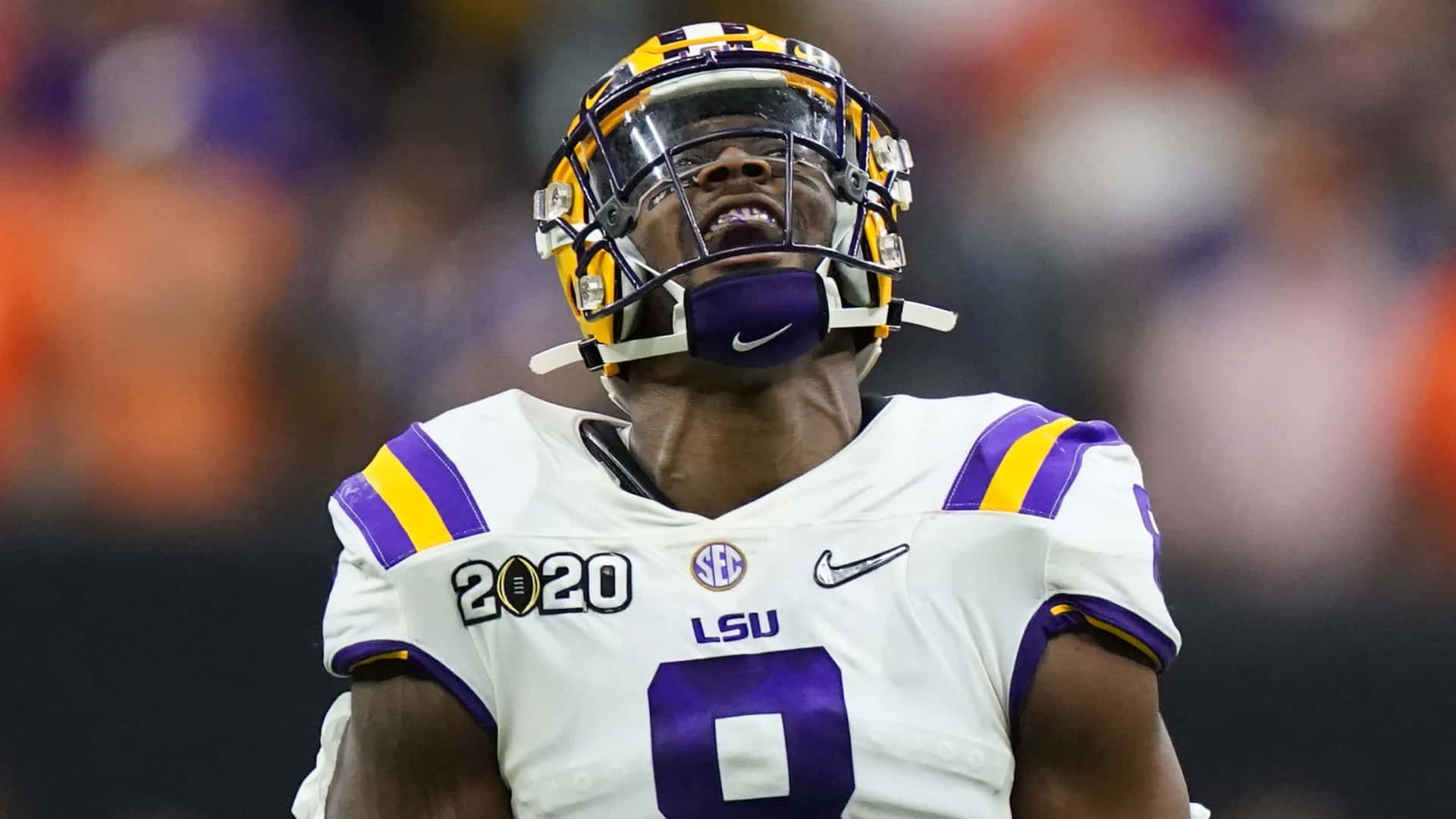 壁紙 — LSU 足球員身穿白色和紫色制服、戴著頭盔，在比賽中抬頭仰望的特寫。