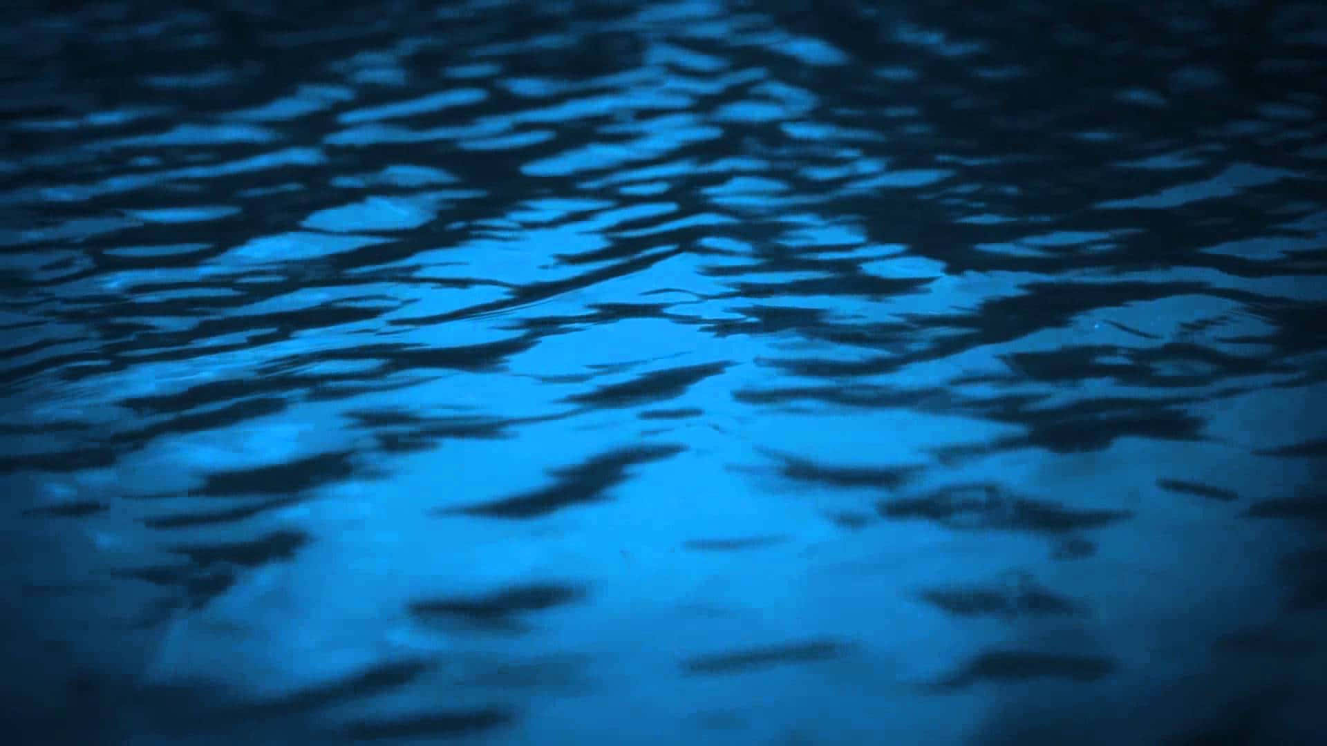  壁紙 — 藍色漣漪水的特寫，深色陰影營造出憂鬱的夜間紋理。