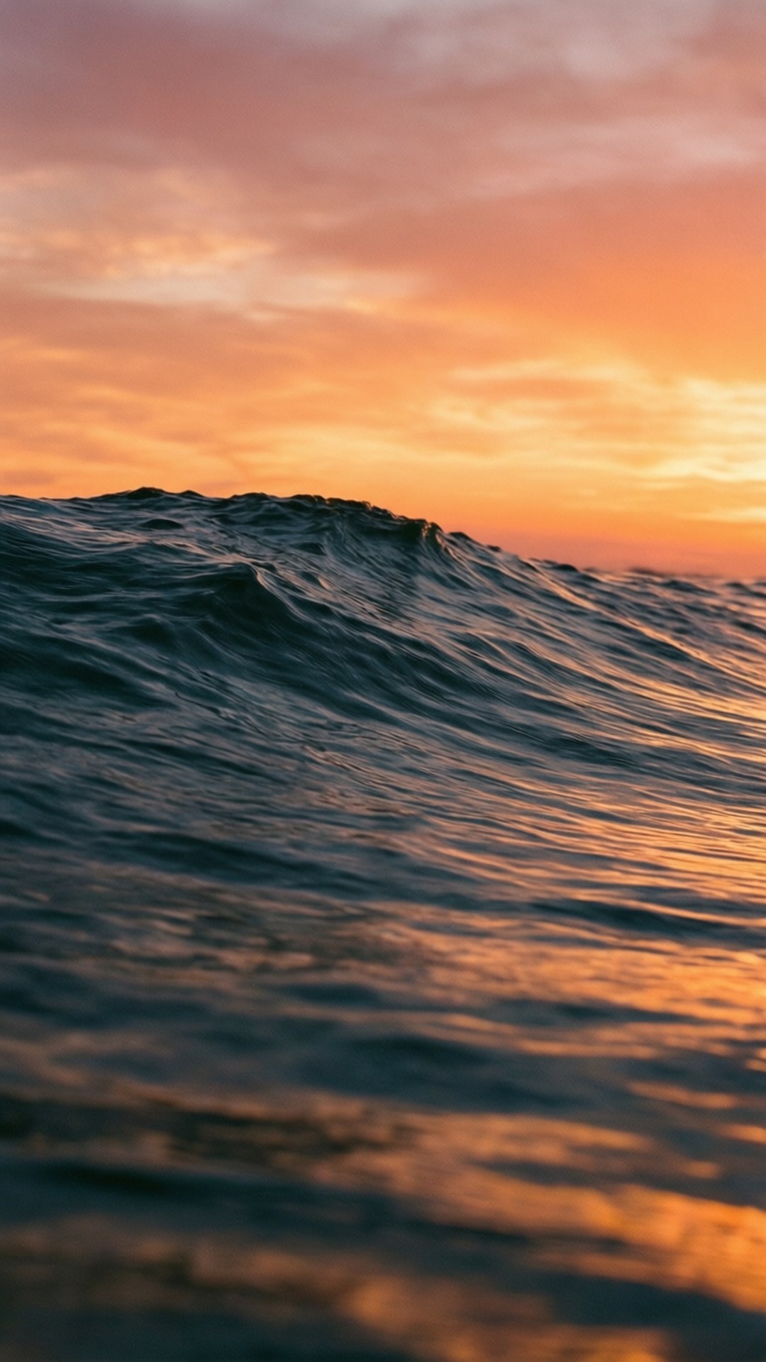 Sunset Waves 壁紙 — 一個滾動的海浪在火橙色和粉紅色的日落天空下破碎的特寫。