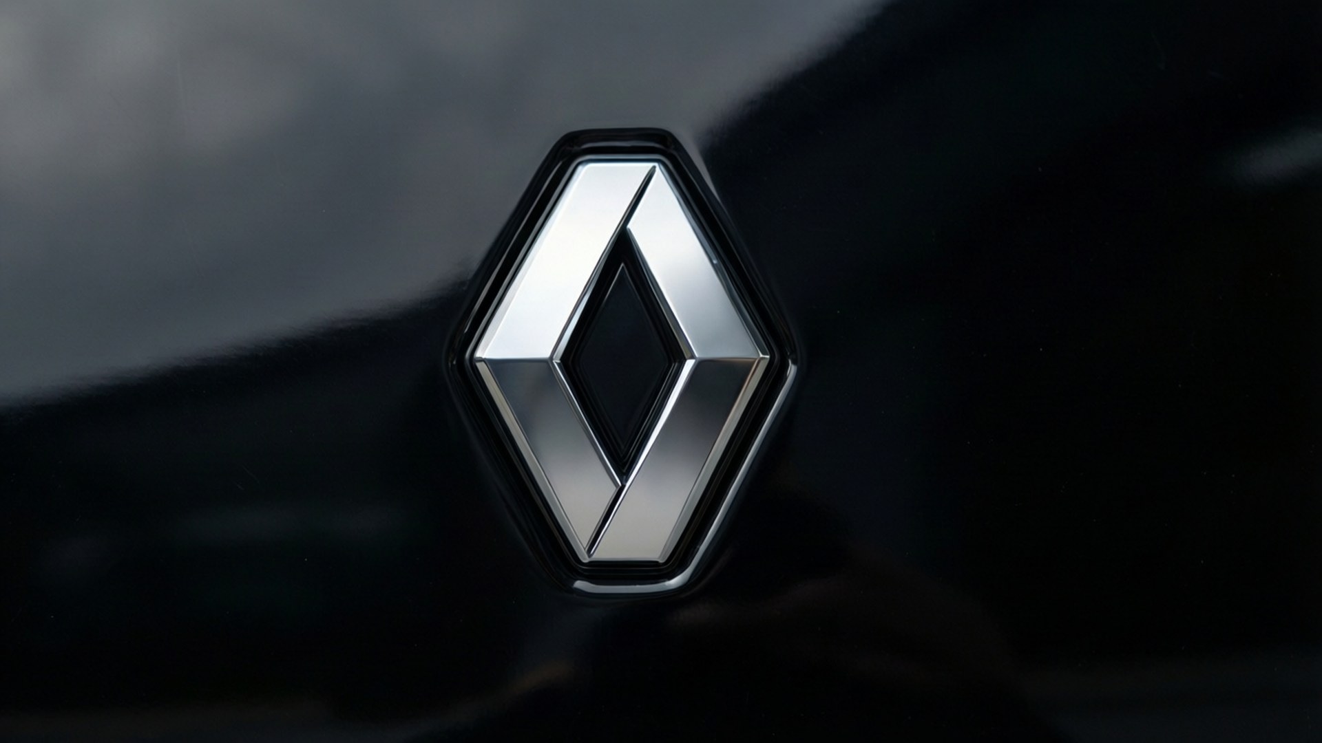 Renault 桌布 壁紙 — 在柔和燈光下，時尚黑色引擎蓋上閃亮的銀色雷諾標誌徽章的近距離特寫。