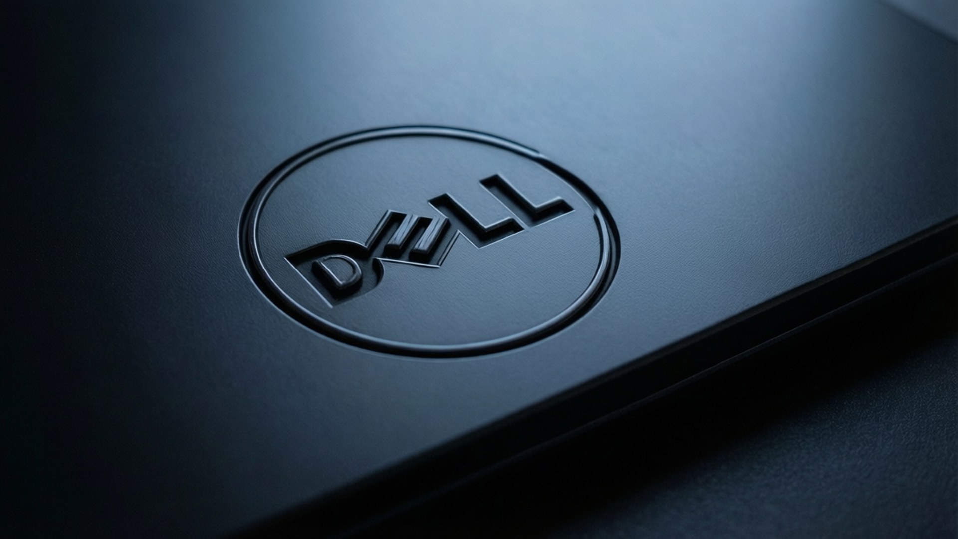 Sleek Dell Logo Close-up 壁紙 — 柔和的定向燈光下，霧面筆記型電腦蓋上壓印的時尚黑色Dell標誌特寫。