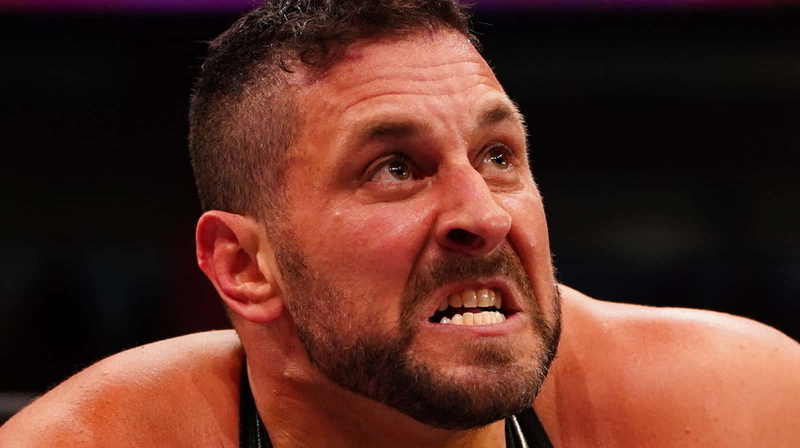  壁紙 — 一名汗流浹背的男性摔角手在明亮的場館燈光下比賽時，露出兇猛表情的特寫。