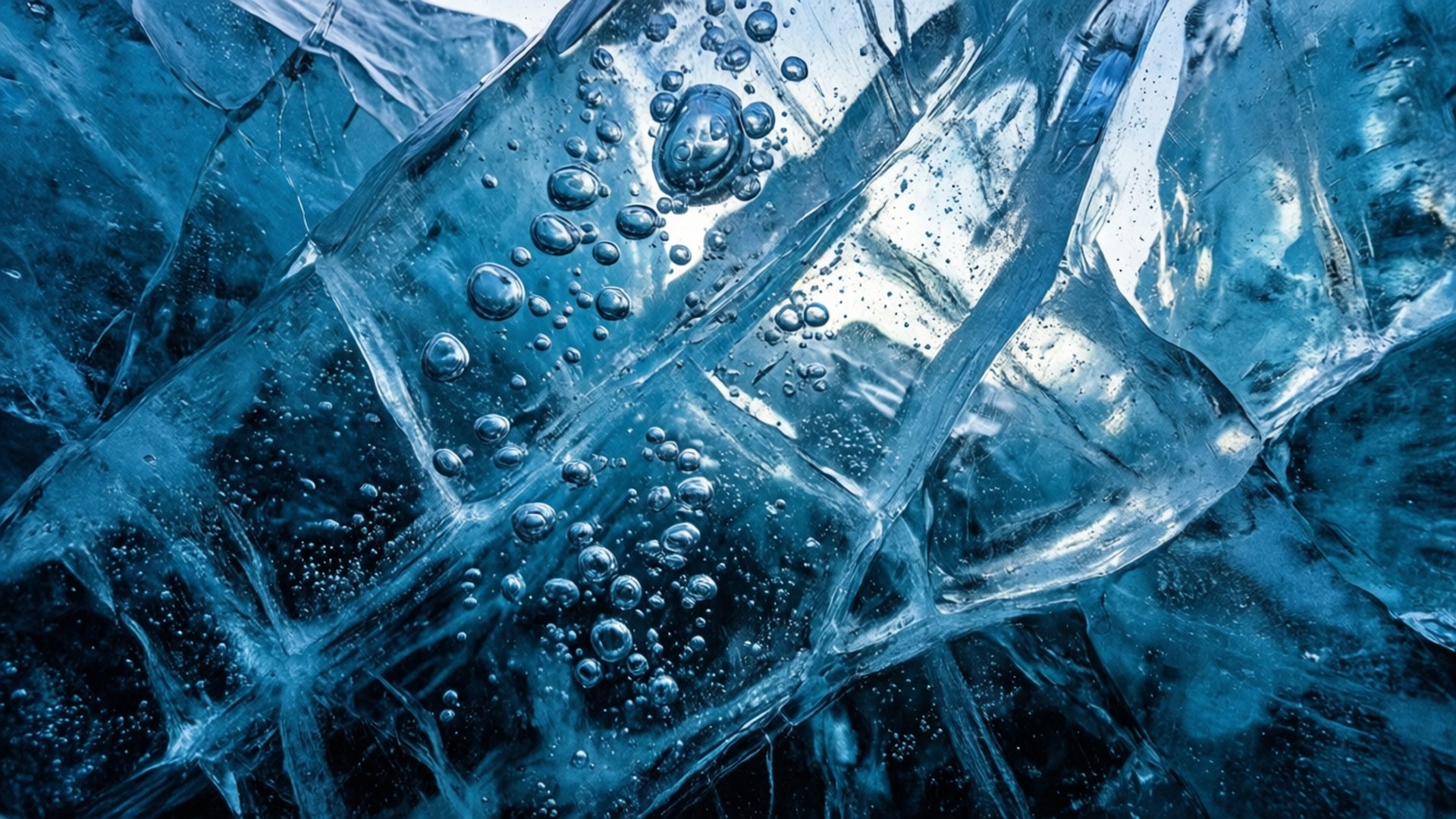 Blue Ice Abstract 壁紙 — 半透明藍色冰塊的特寫，帶有被困氣泡和鋸齒狀晶體裂縫。