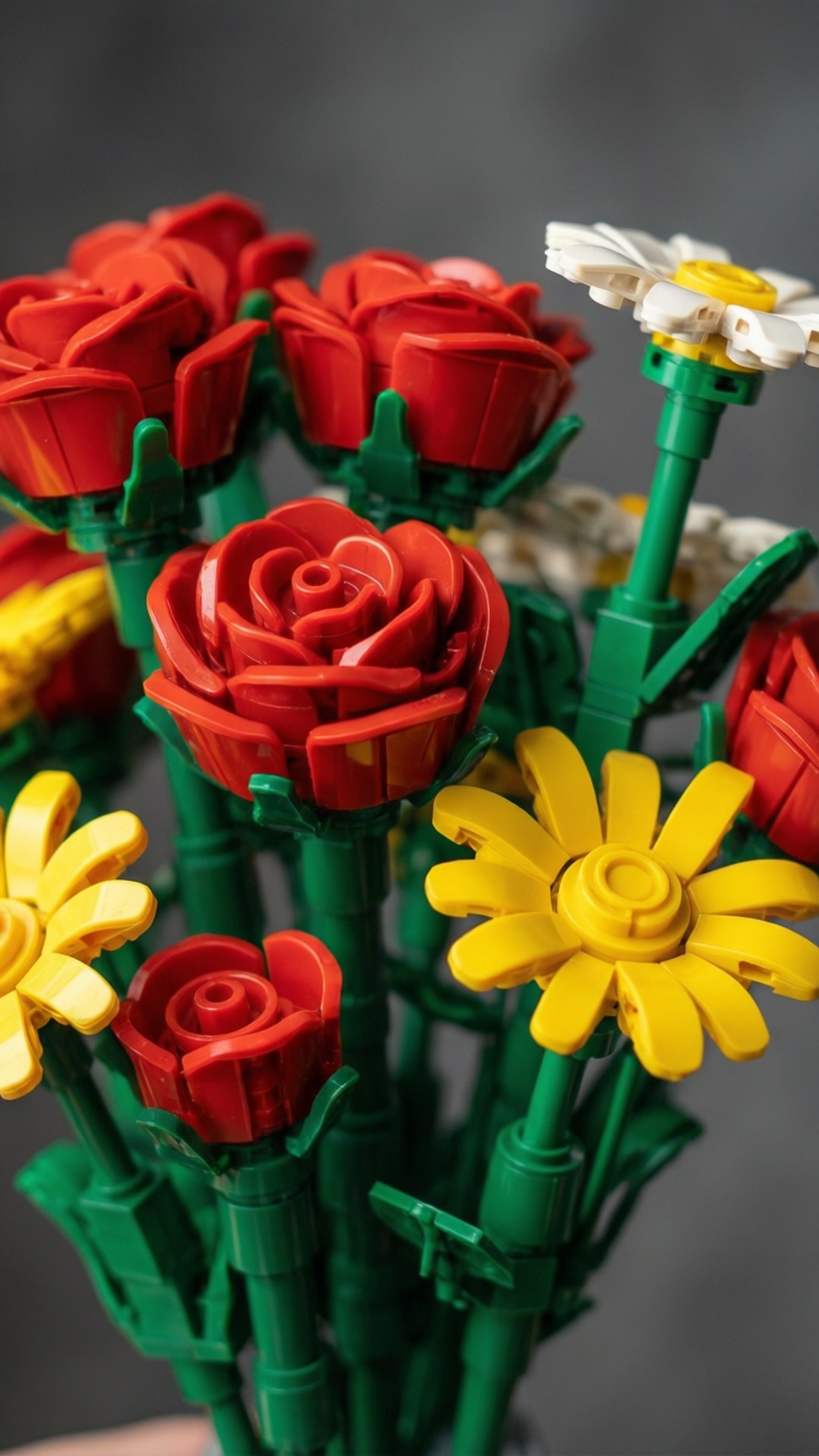Lego Flower Bouquet 壁紙 — 深灰色背景上，包括紅玫瑰和黃雛菊在內的鮮豔LEGO花朵特寫，帶有綠色莖幹。
