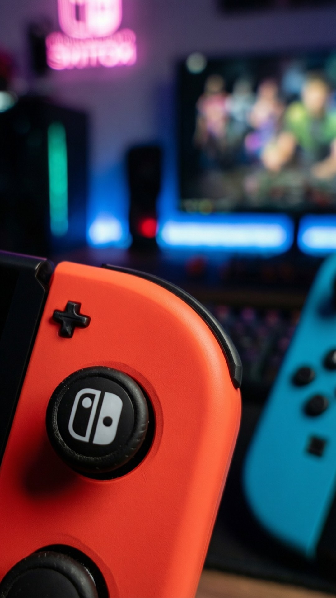 桌布 壁紙 — 發光電視螢幕前顯示遊戲的鮮豔橙色和藍色Nintendo Switch Joy-Con控制器特寫。