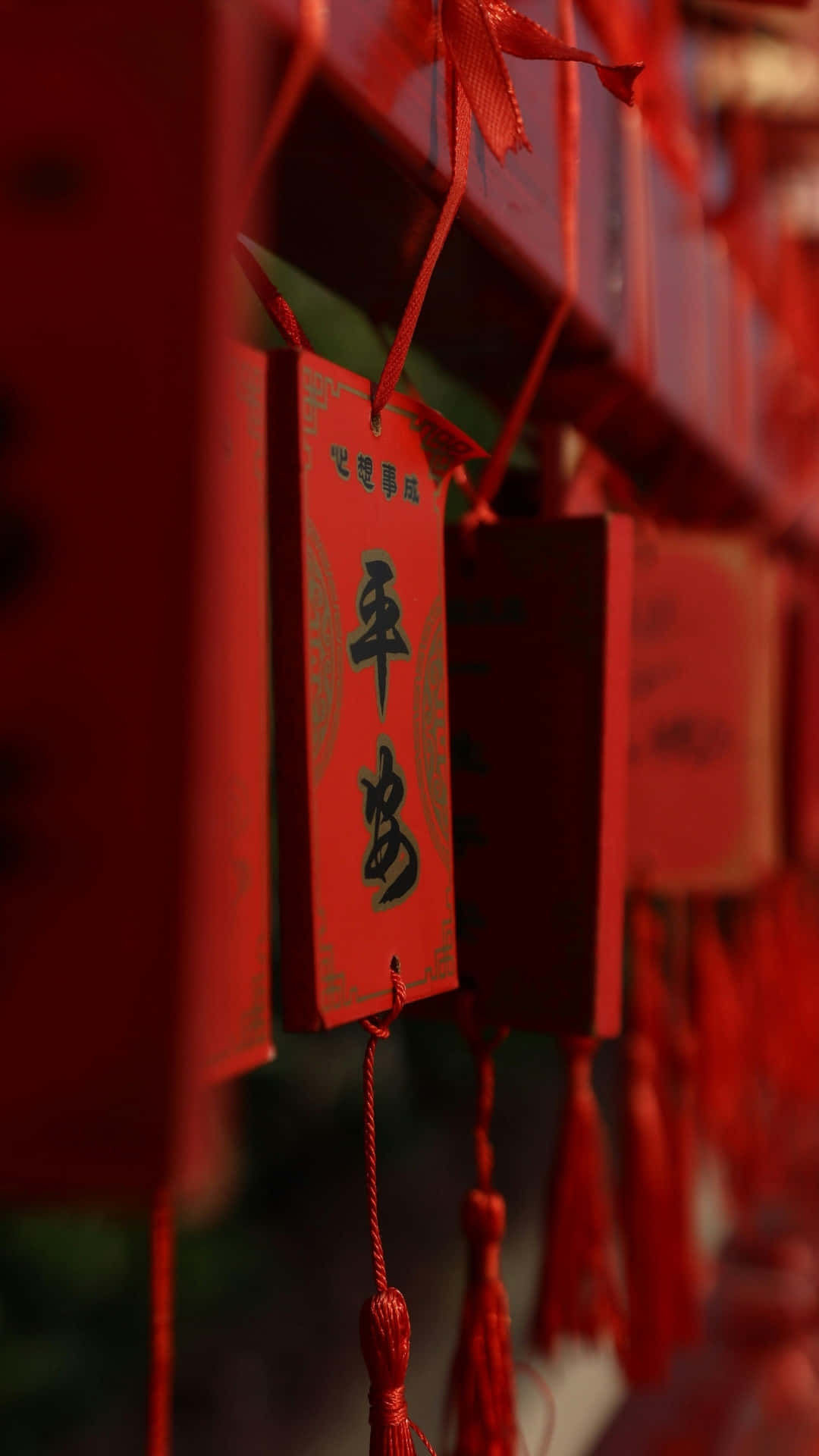  壁紙 — 鮮紅色祈福標籤的特寫，上面有黑色中文字，用紅絲帶和流蘇綁成一排懸掛。