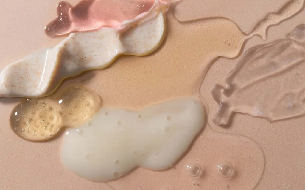 Vanilla Girl 桌布 壁紙 — 黏稠的粉彩色液體在柔軟的桃色表面上匯聚和滴落的特寫，帶有可見的氣泡。