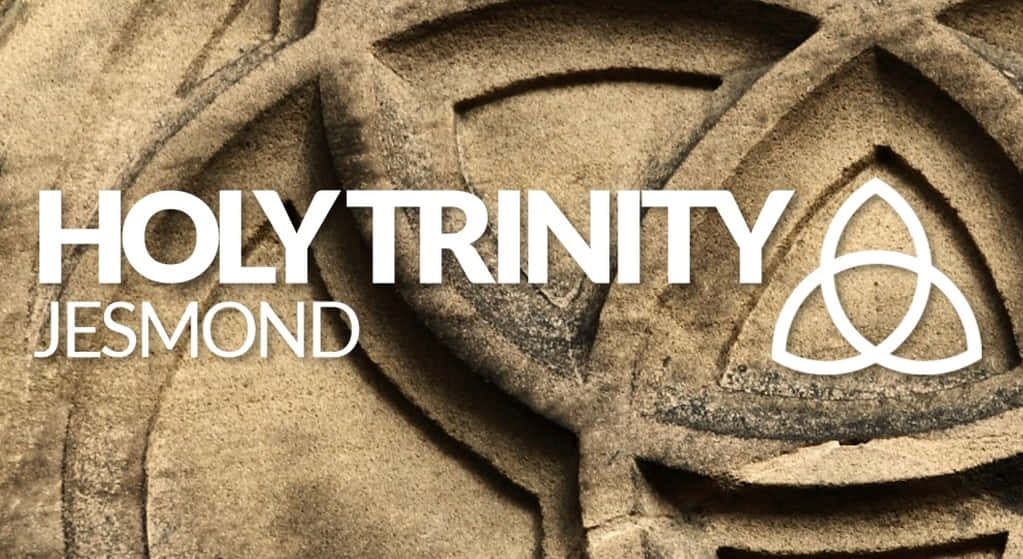  壁紙 — 風化石雕的特寫，上面有白色文字的「HOLY TRINITY JESMOND」和三位一體結符號。