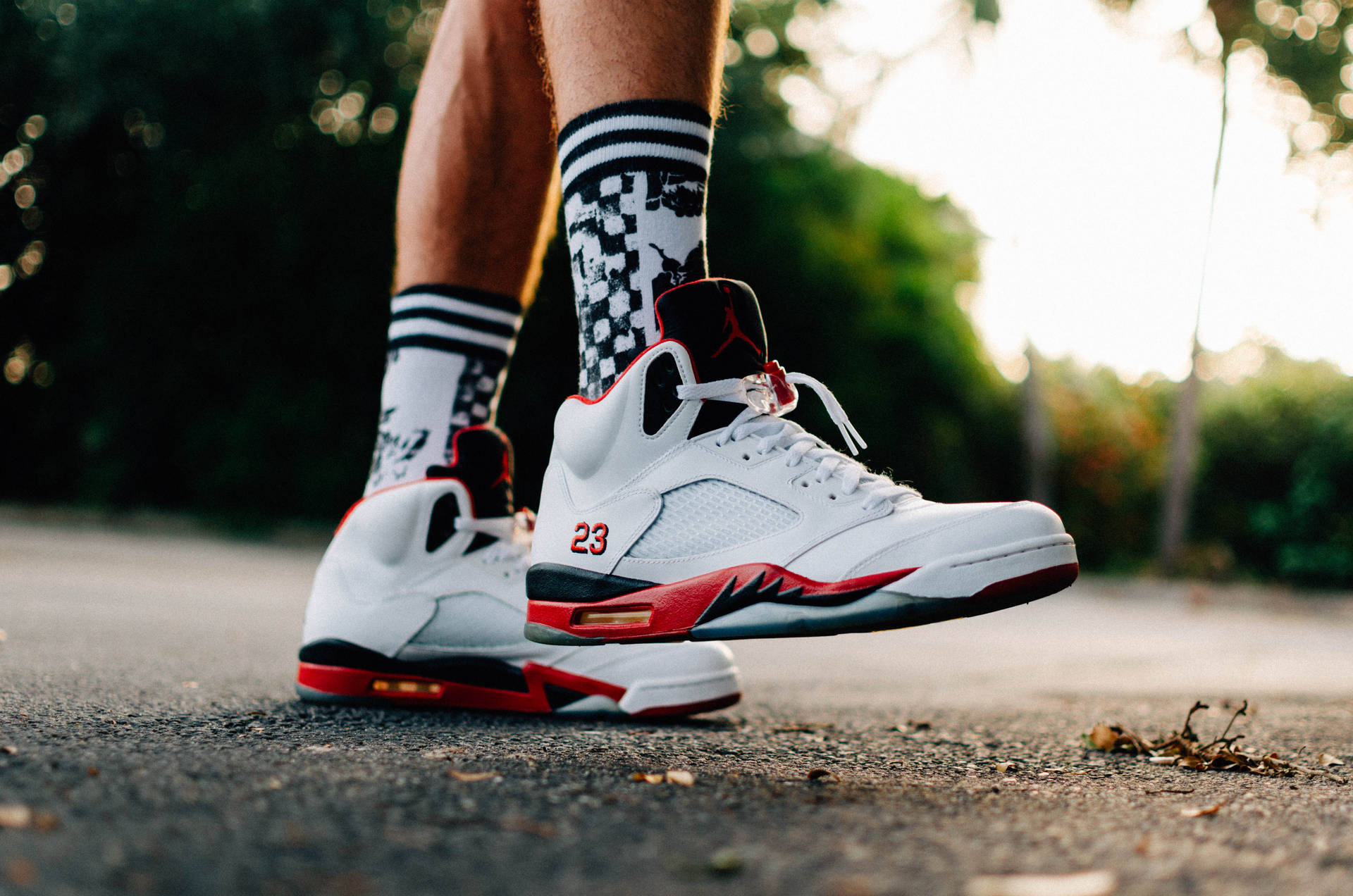 日落時分人行道上白色、紅色和黑色Air Jordan 5運動鞋配格紋襪。 — Jordan Logo 壁紙