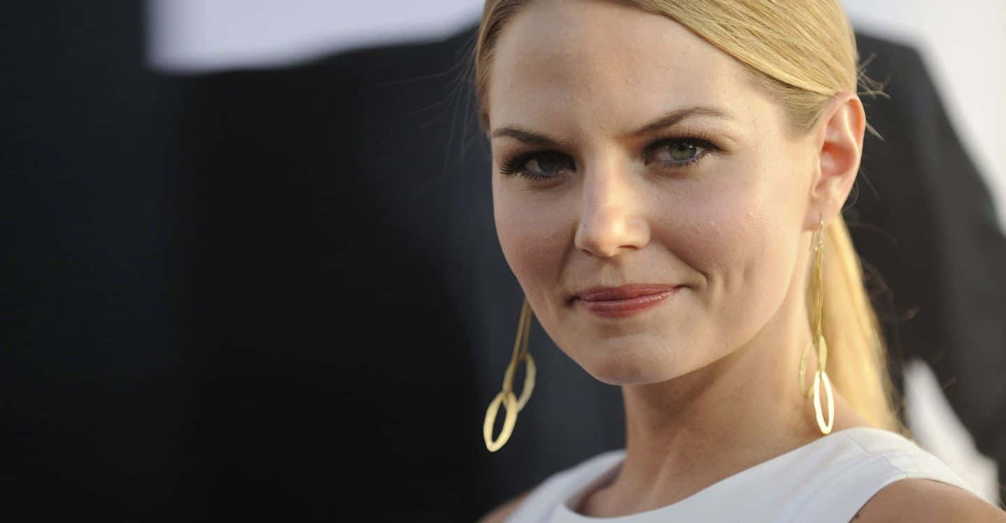 jennifer morrison 桌布 壁紙 — 一位金髮碧眼的女人戴著金色圓環耳環和白色上衣，在黑暗模糊的背景下的特寫肖像。