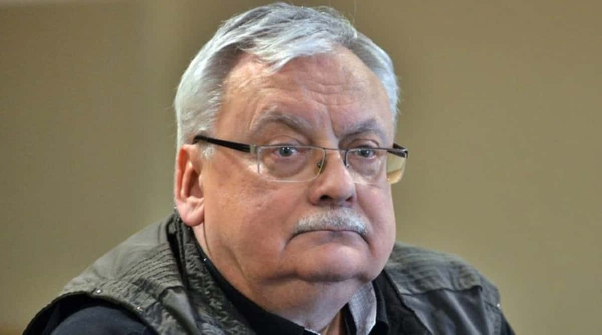 Andrzej Sapkowski 桌布 壁紙 — 嚴肅年長男士的頭像特寫，灰白頭髮，戴眼鏡，身穿深色背心。
