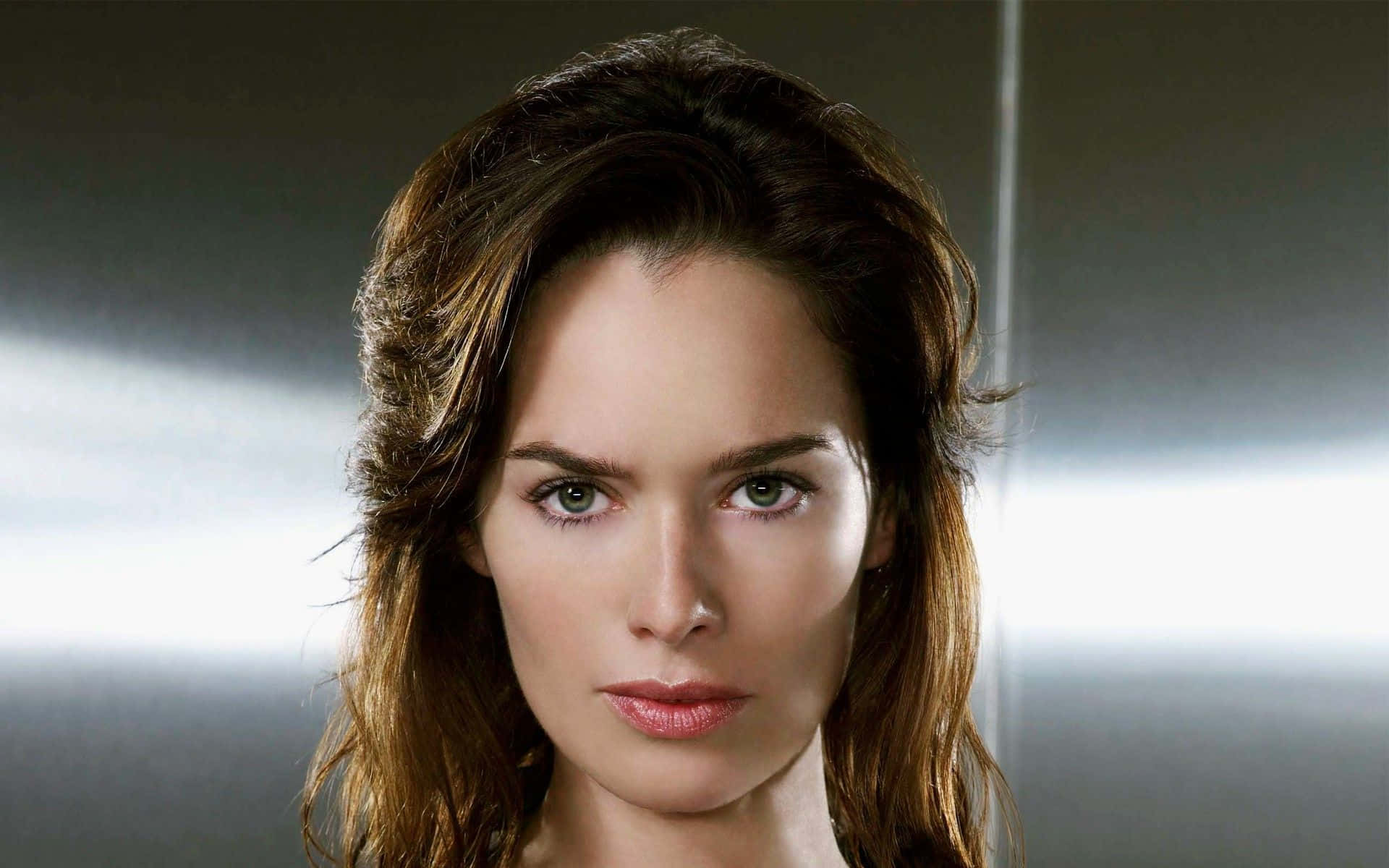 Lena Headey 桌布 壁紙 — 一個特寫肖像，一位棕色頭髮和綠色眼睛的女性在柔和照明的灰色背景下直視相機。