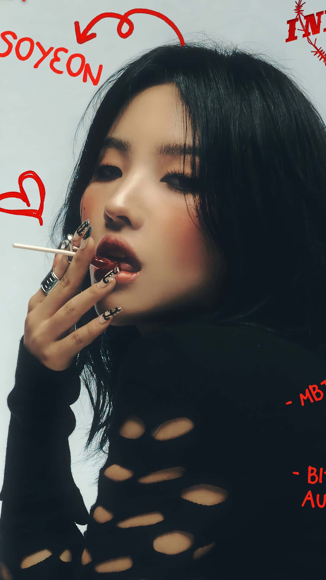  壁紙 — 一位深色頭髮、妝容大膽的女性，穿著黑色破洞上衣，用唇掃塗抹紅色唇膏的特寫肖像。