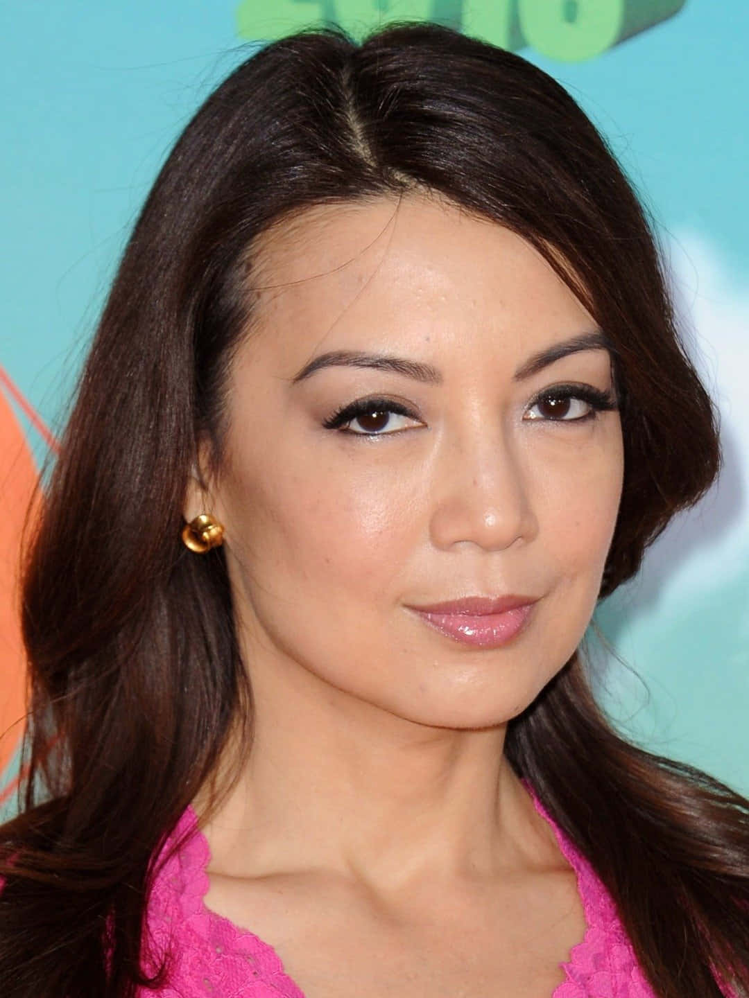 Ming Na Wen 桌布 壁紙 — 一個特寫肖像，一位深色頭髮、身穿粉紅色上衣的女性，背景是色彩繽紛的模糊效果。