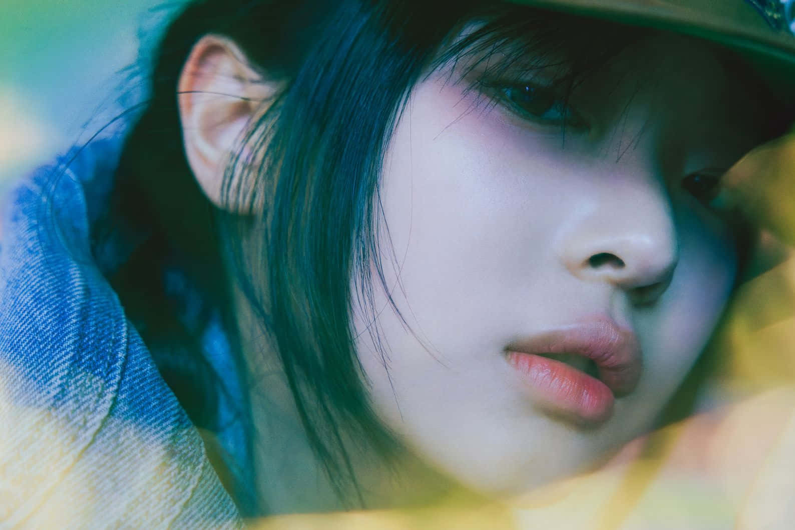  壁紙 — 年輕黑髮女子戴帽在冷藍和暖黃燈光下的特寫肖像。