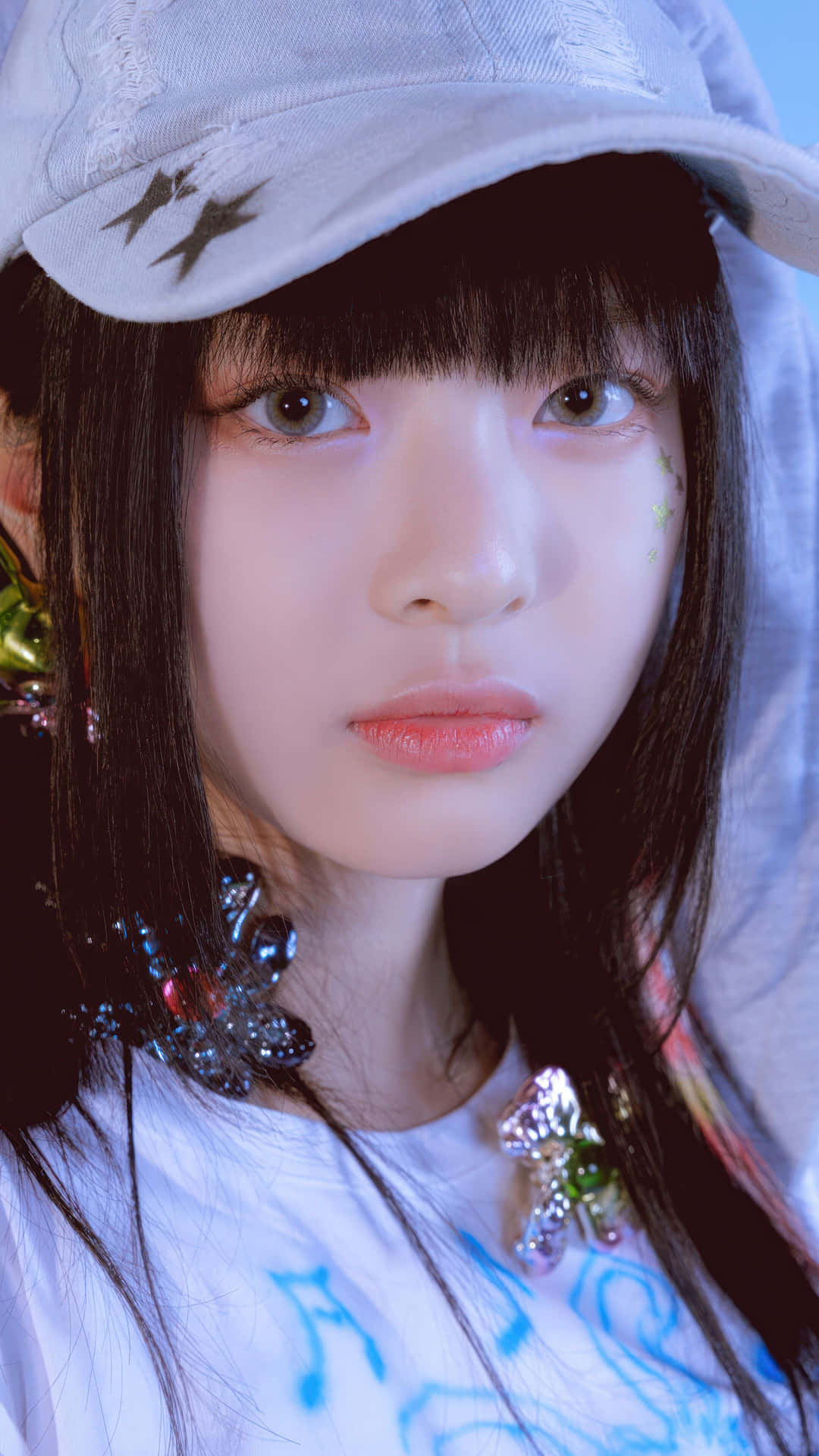  壁紙 — 年輕黑髮女子戴白色帽子及色彩繽紛閃亮配飾，在冷色藍光下的特寫肖像。